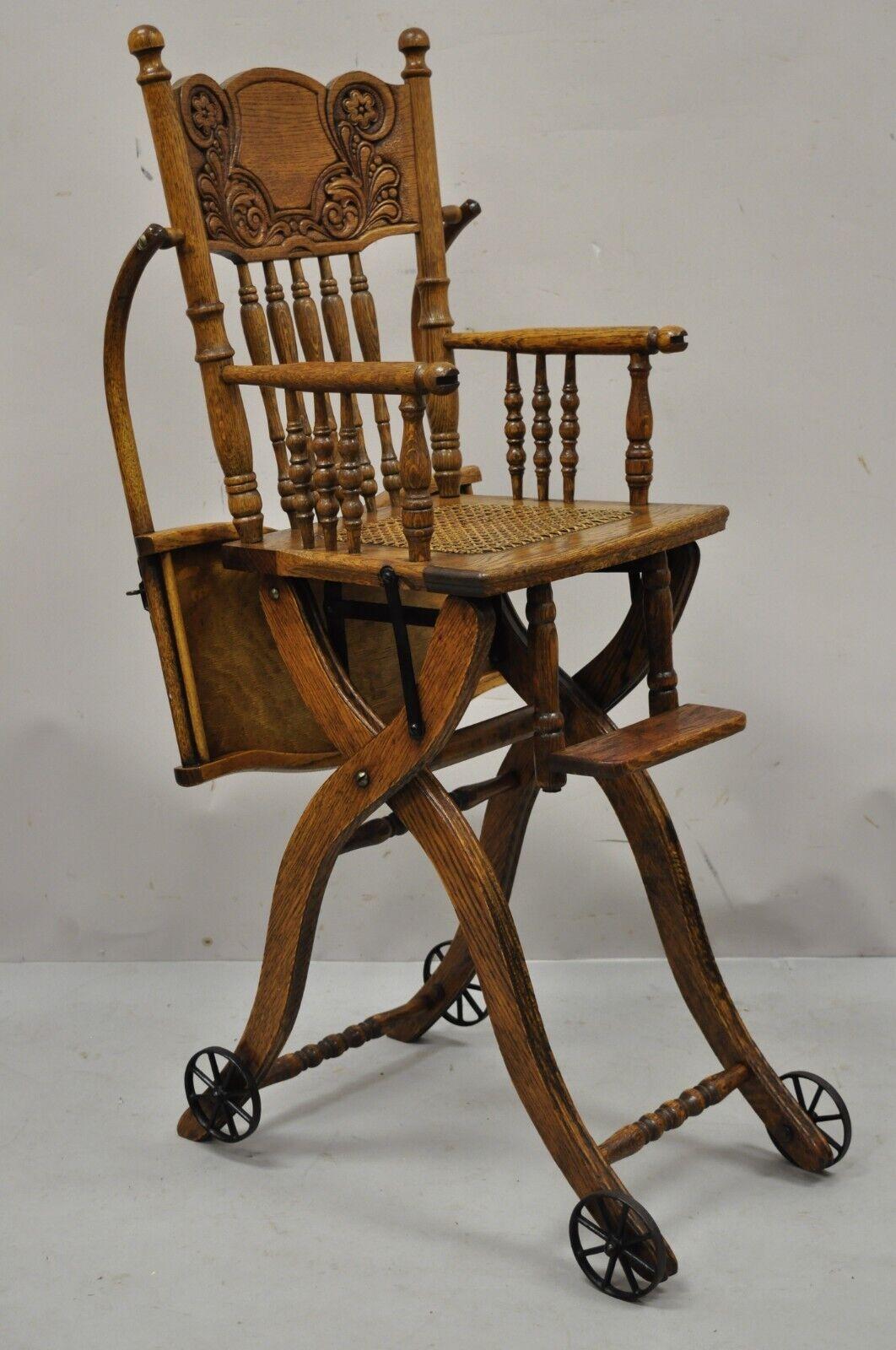 Antique Victorian Oak Wood Convertible Combination Baby High Chair Stroller. Item features cast iron hardware, cane seat, iron rolling wheels, carved pressed back, very nice antique item, adjustable form from high chair to low rolling play chair.