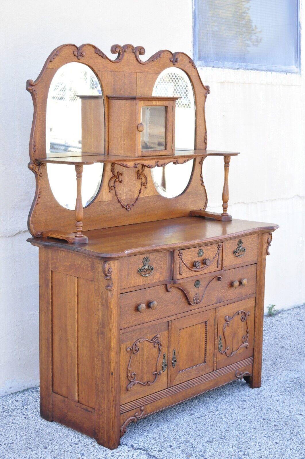 Antique Victorian Olbrich and Goldbeck oak wood buffet sideboard cabinet with mirror. Item features (2) Oval beveled glass mirrors, upper shelf with small swing door, carved drape accents, 2 part construction, 3 swing doors, original label, 4