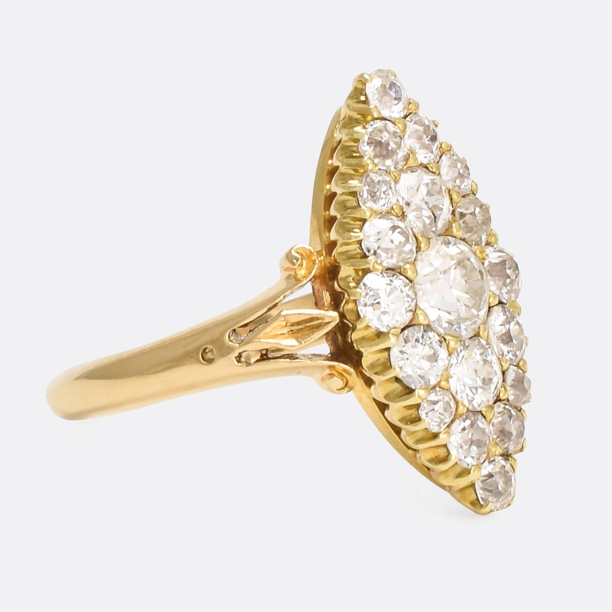 A sparkling turn of the century diamond cluster ring, the marquise shaped head set with 1.5cts of chunky old mine cut diamonds. With trifurcated scrolled shoulders and tapered band, all in 18ct gold. A great flash with particularly bright stones.