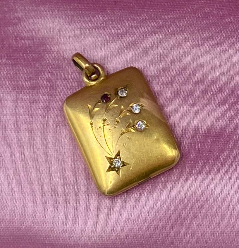 A gorgeous Victorian - Belle Epoque Picture locket pendant set with four Old Mine Cut Diamonds and a Ruby in a star and flower motif design.  The locket is the most stunning warm brushed 14 Karat Rose Gold.  The wonderful image on the front is of a