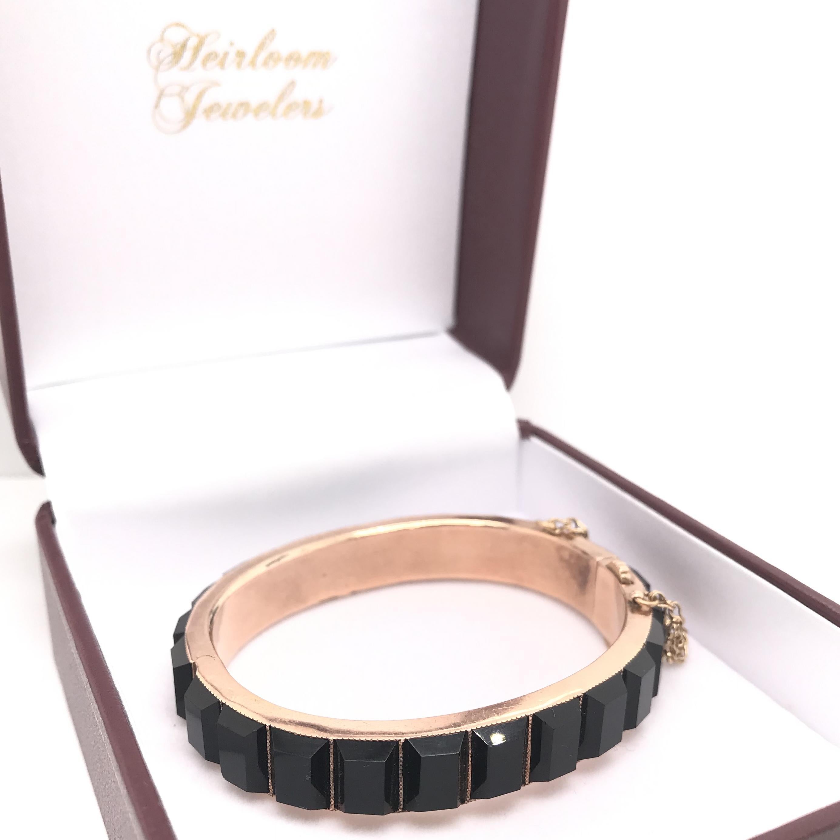 This stunning antique piece was crafted sometime during the Victorian design period (1840-1900). Bold step cut onyx encompass the entire length of the bangle. The setting was crafted from 14K Victorian rose gold. Victorian rose gold is typically a