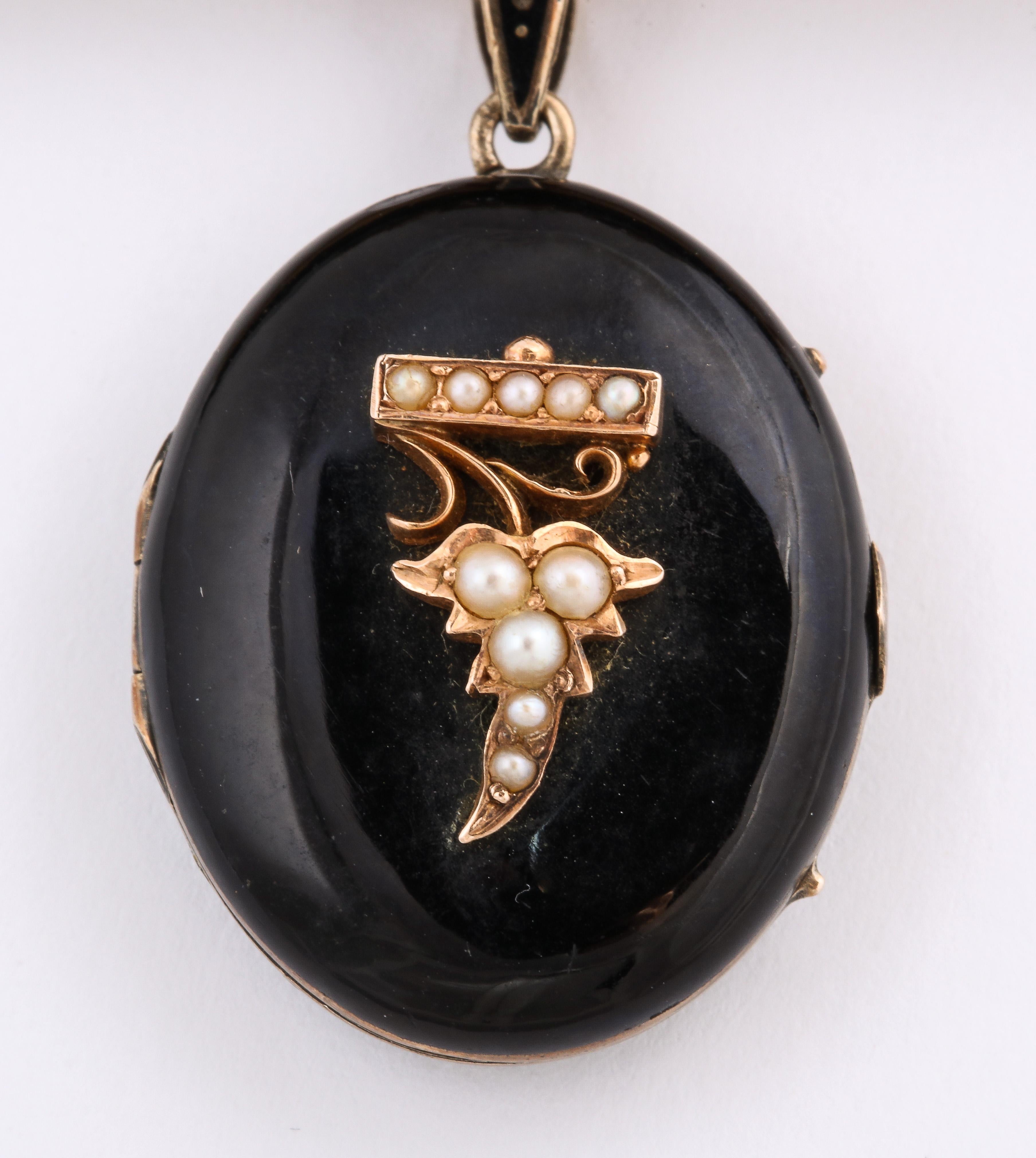 A length of onyx, 14 Kt gold and natural pearls, suspends an enamel locket with its small bale dotted with gold. At top the pearls seem to be cupid's arrow pointing to the bunch of pearl grapes on the locket below. Pearls symbolize tears and thus