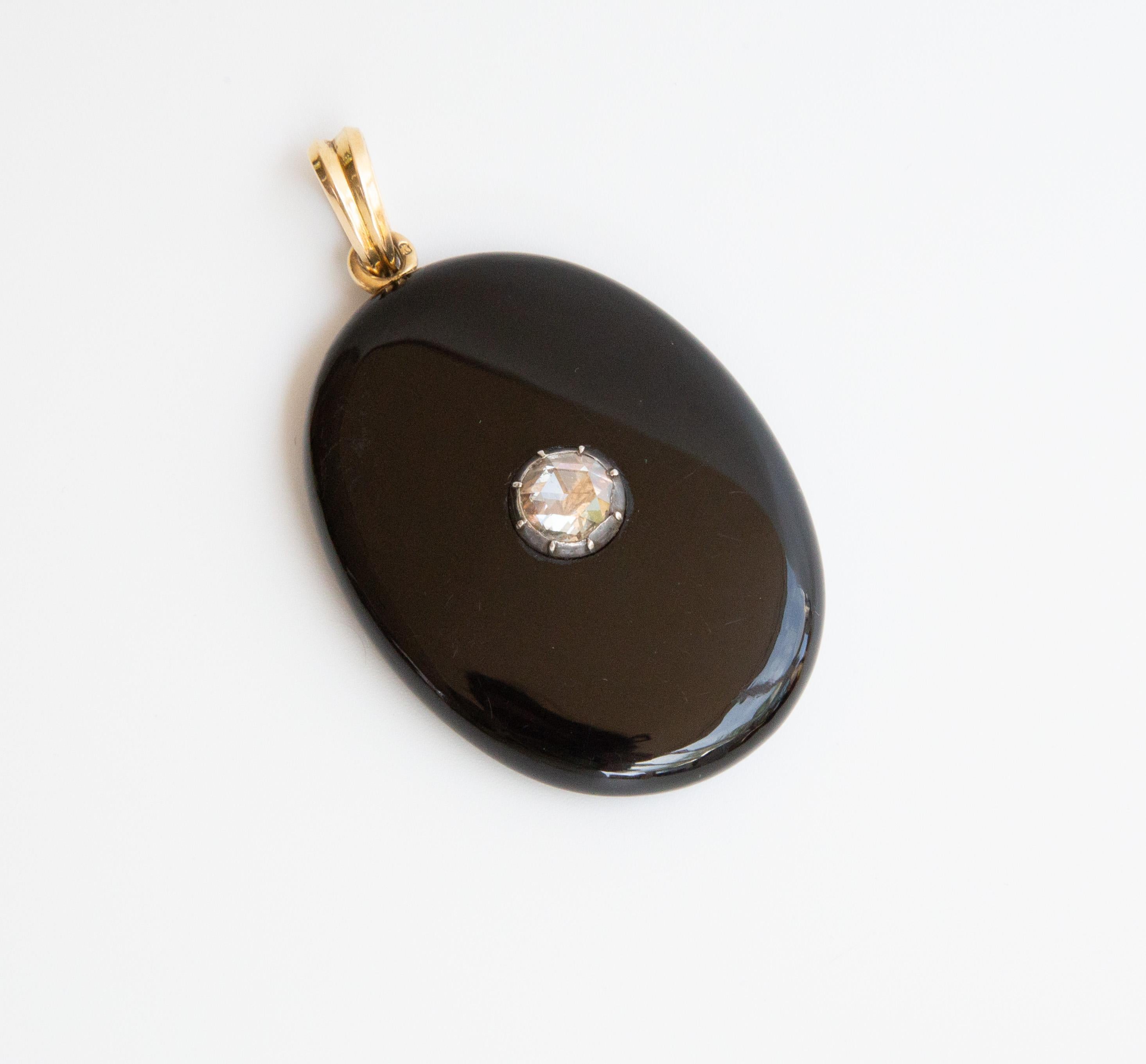 An antique Victorian oval onyx locket /pendant set with a rose cut diamond (approximately 1 carat). The  diamond is placed in a silver foil. The pendant features on the back side a locket to store a mini photograph or a tiny item. The locket closes