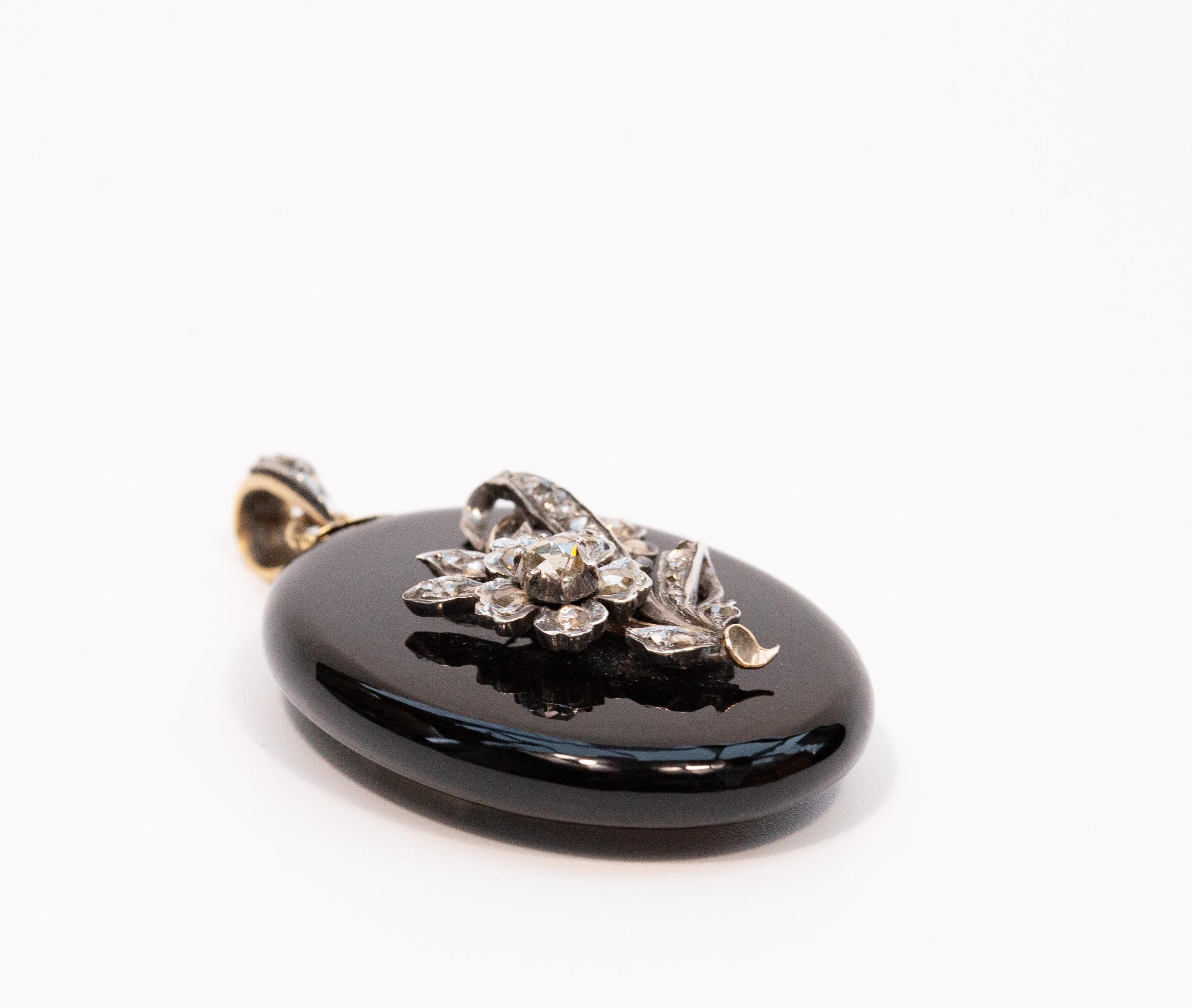 An antique Victorian oval onyx locket /pendant with a flower decoration. The decoration is made of  rose cut diamonds set in silver. The pendant features on the back side a locket to store a mini photograph or a tiny item that can be closed with a