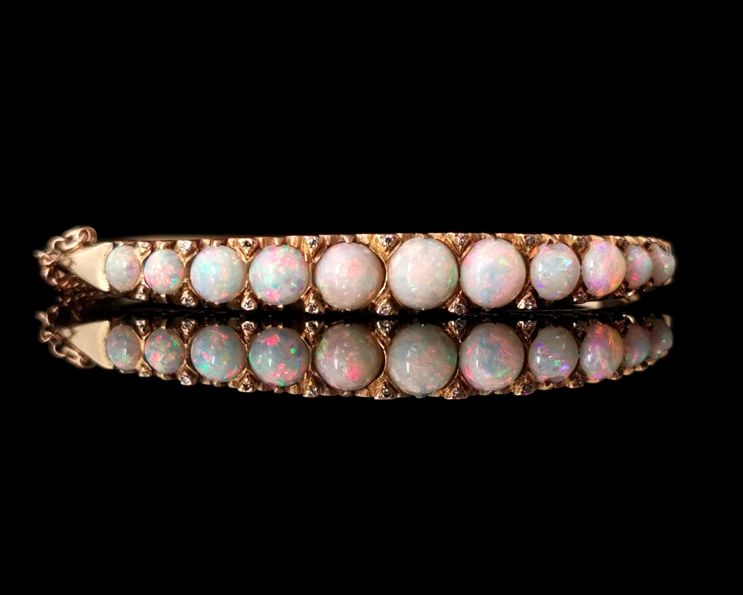 A stunning antique, Victorian era, Opal and diamond bangle.

Crafted from smooth 9karat yellow gold the chunky bangle features a front centre row of beautifully coloured opals, intercepted to the top and bottom by diamond chips giving extra