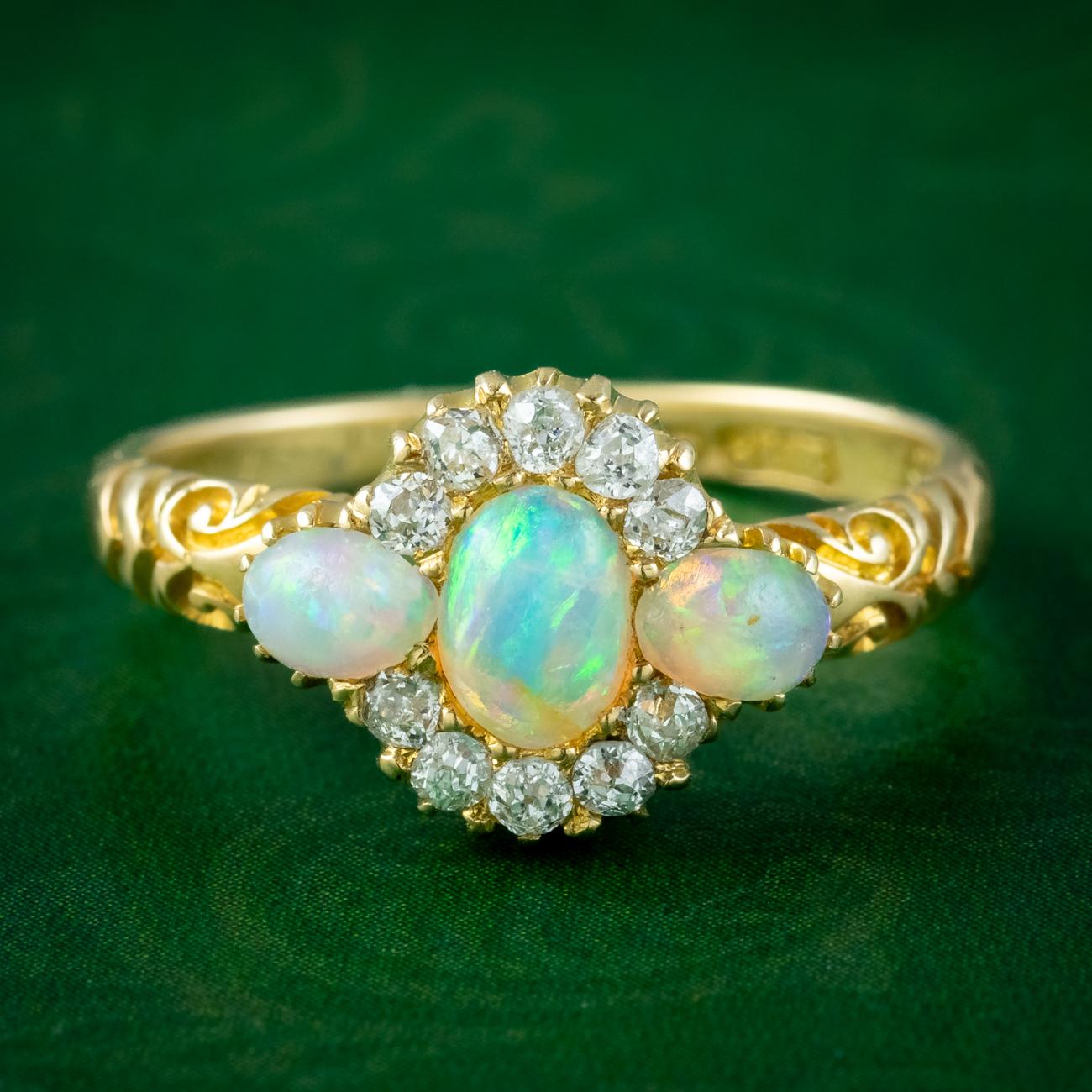 A fabulous antique late Victorian cluster ring adorned with a trilogy of natural opal cabochons along the centre (approx. 0.70ct total) haloed by ten twinkling old mine cut diamonds (approx. 0.30ct total).

Opal is the birthstone of October. Their