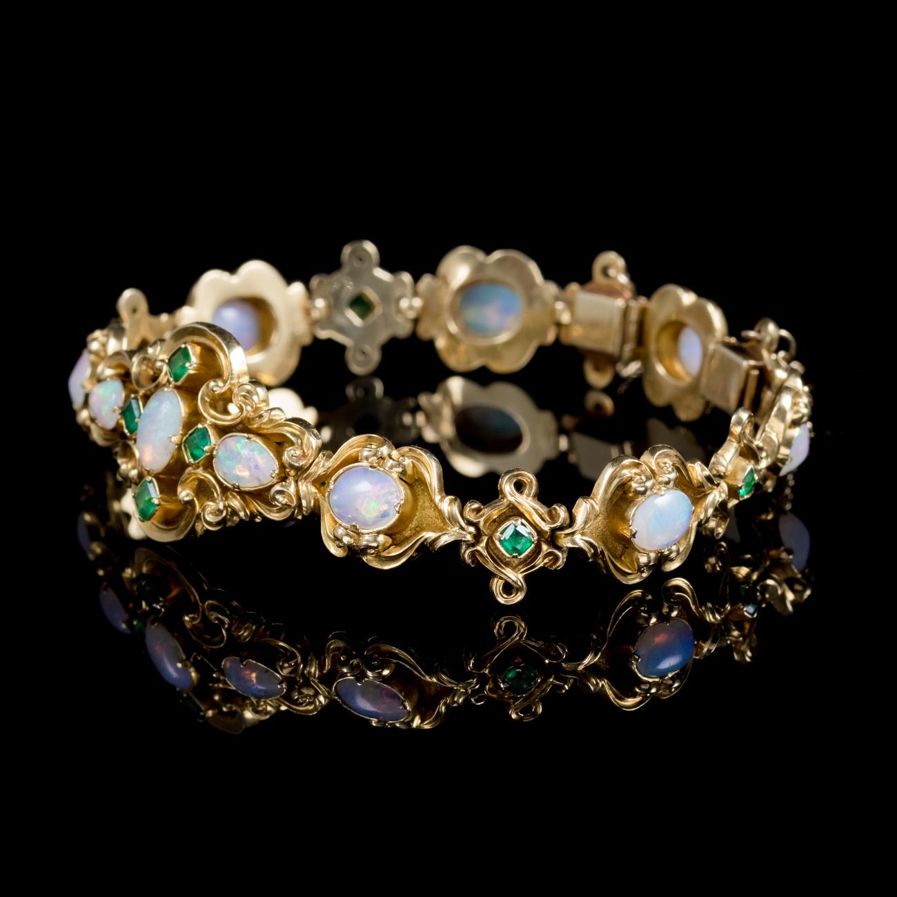 A grand antique Victorian bracelet decorated with beautiful Opals and green Emeralds. The Opals are a kaleidoscope of rainbow colours shimmering and changing colours with the light. They radiate blues, pinks, greens, turquoise and an inner orange.