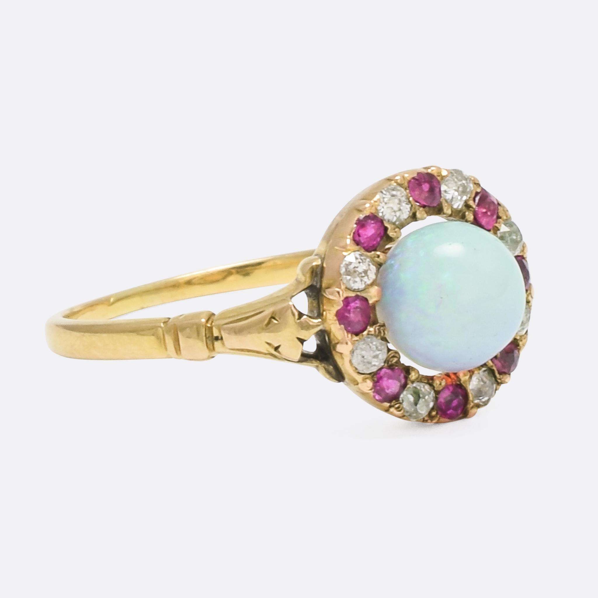 A beautiful antique Victorian cluster ring dating from c.1860. The central stone is a vibrant blue/green opal, cut into a nearly spherical cabochon that looks like a little planet Earth; it's surrounded by a halo or alternating diamonds and rubies.