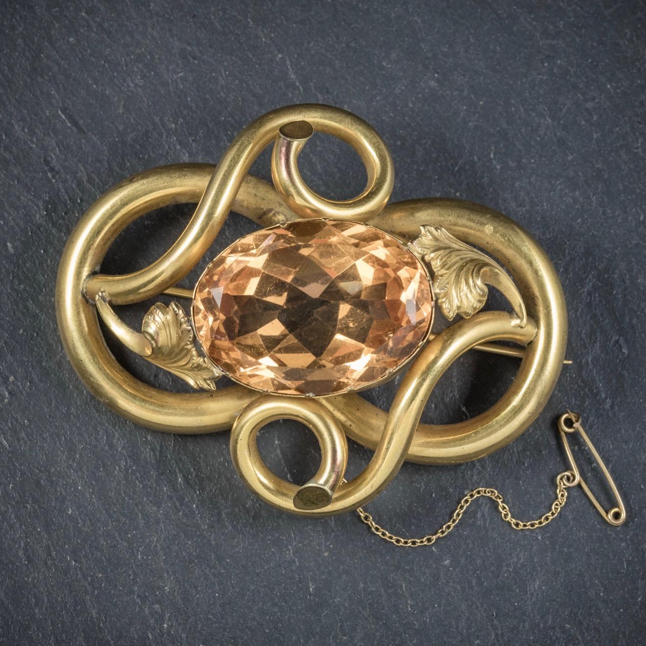 A grand antique Pinchbeck knot brooch that was beautifully made during the Victorian era, Circa 1880. 

The lovely piece is adorned with a large orange Paste Stone in the centre which glistens with a warm, radiant glow that simulates a Citrine.