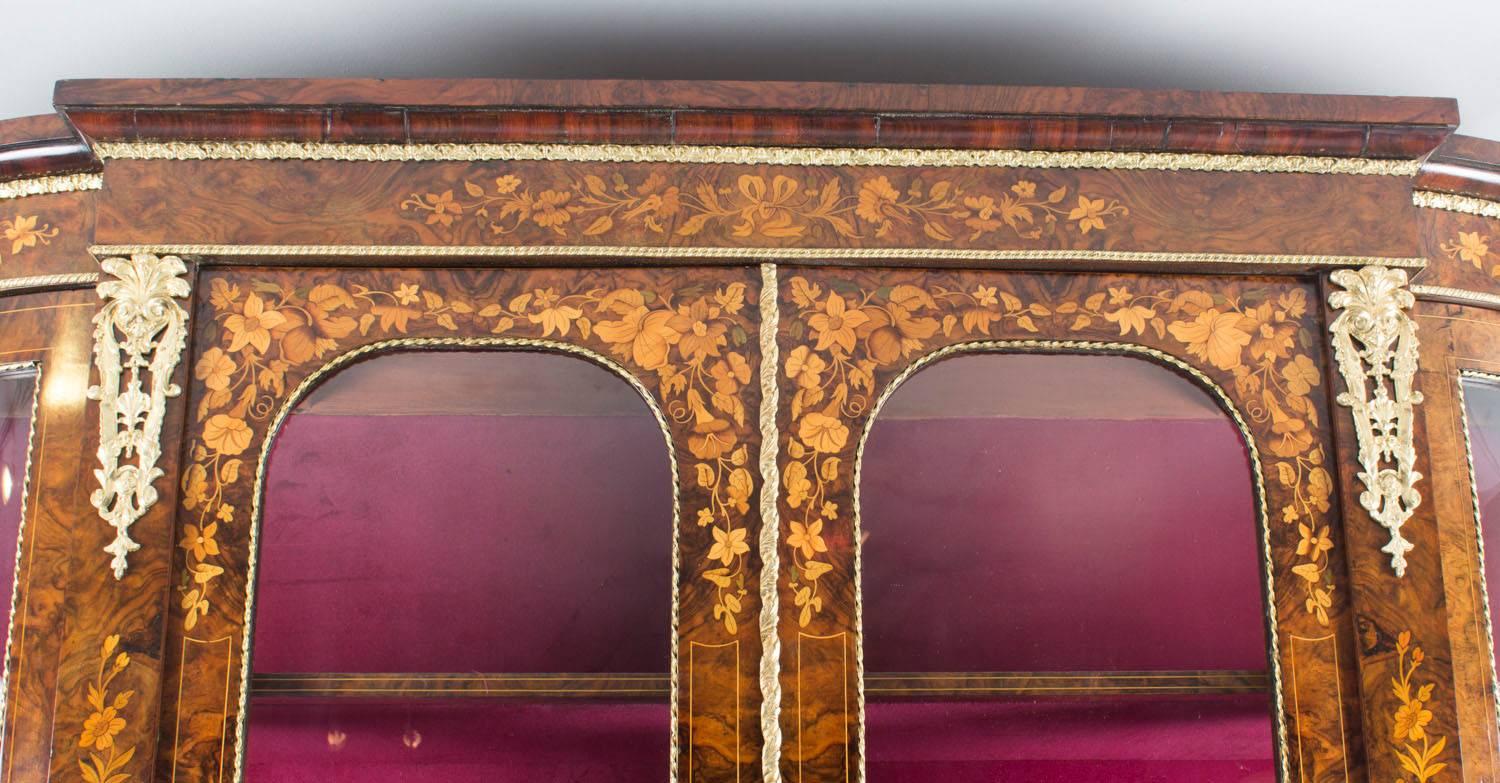 This is a fabulous antique Victorian ormolu-mounted burr walnut and fruitwood marquetry display cabinet by Edwards & Roberts, circa 1860 in date.

It is inlaid with urns of assorted flowers, floral trails and foliage. The entire piece highlights the