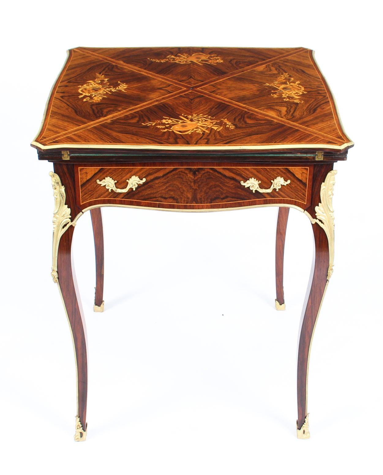 This is a wonderful antique Victorian ormolu-mounted envelope card table, circa 1880 in date.

The card table is made from superb quality Gonçalo Alves, has the most striking musical instrument marquetry decoration on each leaf and superb gilded