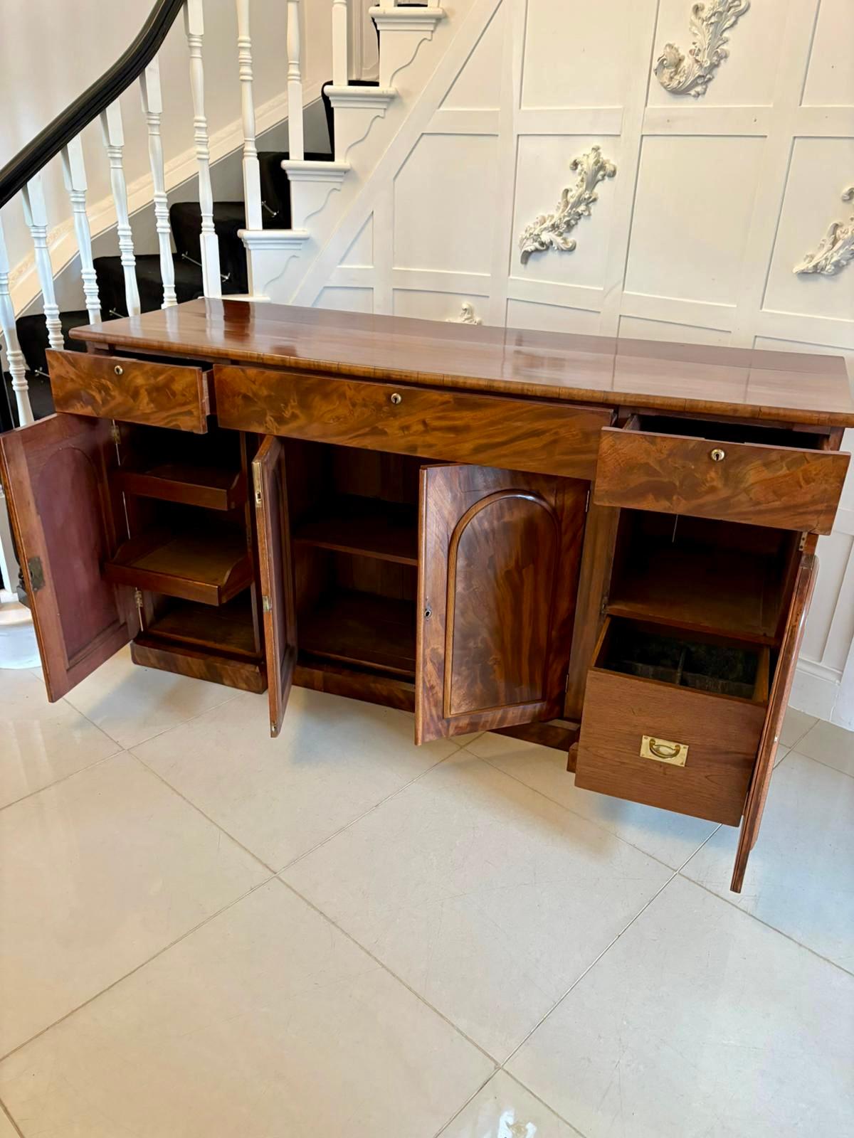 Antica credenza vittoriana di eccezionale qualità in mogano figurato con un piano in mogano figurato di ottima qualità con 3 cassetti sopra 4 porte modellate in mogano figurato a pannelli ad arco che si aprono per rivelare una celletta, ripiani e