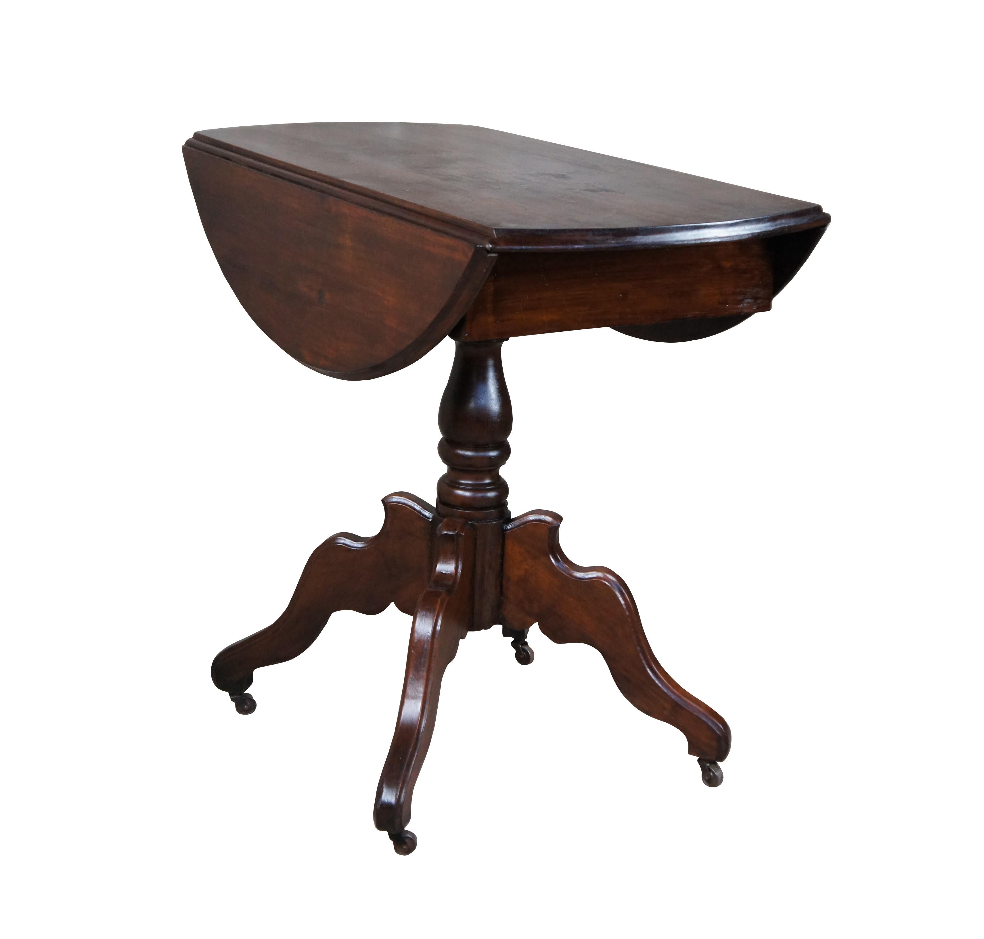 Late Victorian walnut drop leaf table.  Features an oval form over a turned baluster base leading to a four legged base with downswept legs and casters.  

Dimensions:
34