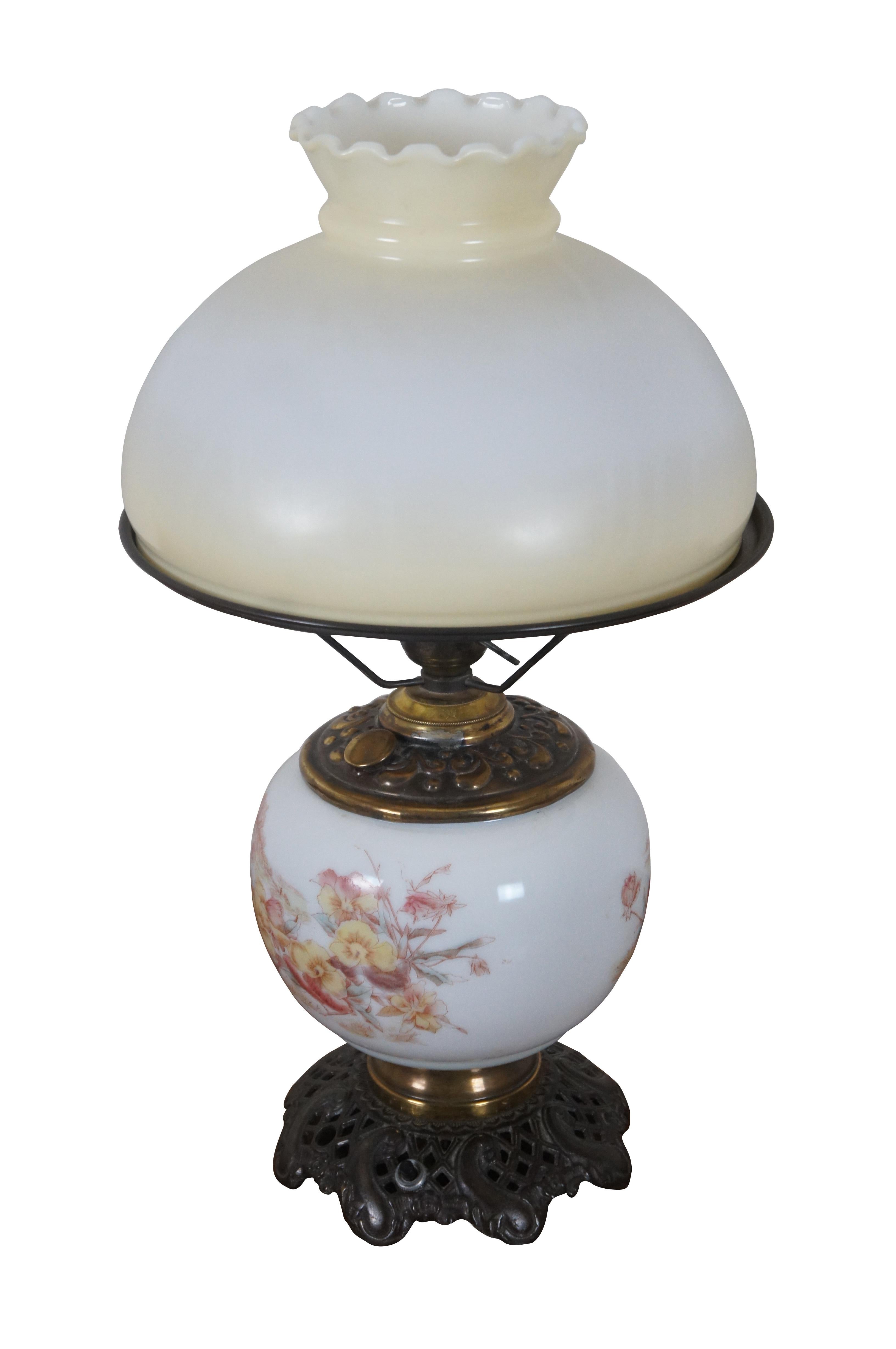 Antique Gone with the Wind oil lamp (converted to electric) featuring a lightly tinted, ruffled top, milk glass shade, and a milk glass reservoir printed with pink and yellow pansies. Base marked 42. Three way switch allows upper portion and lower