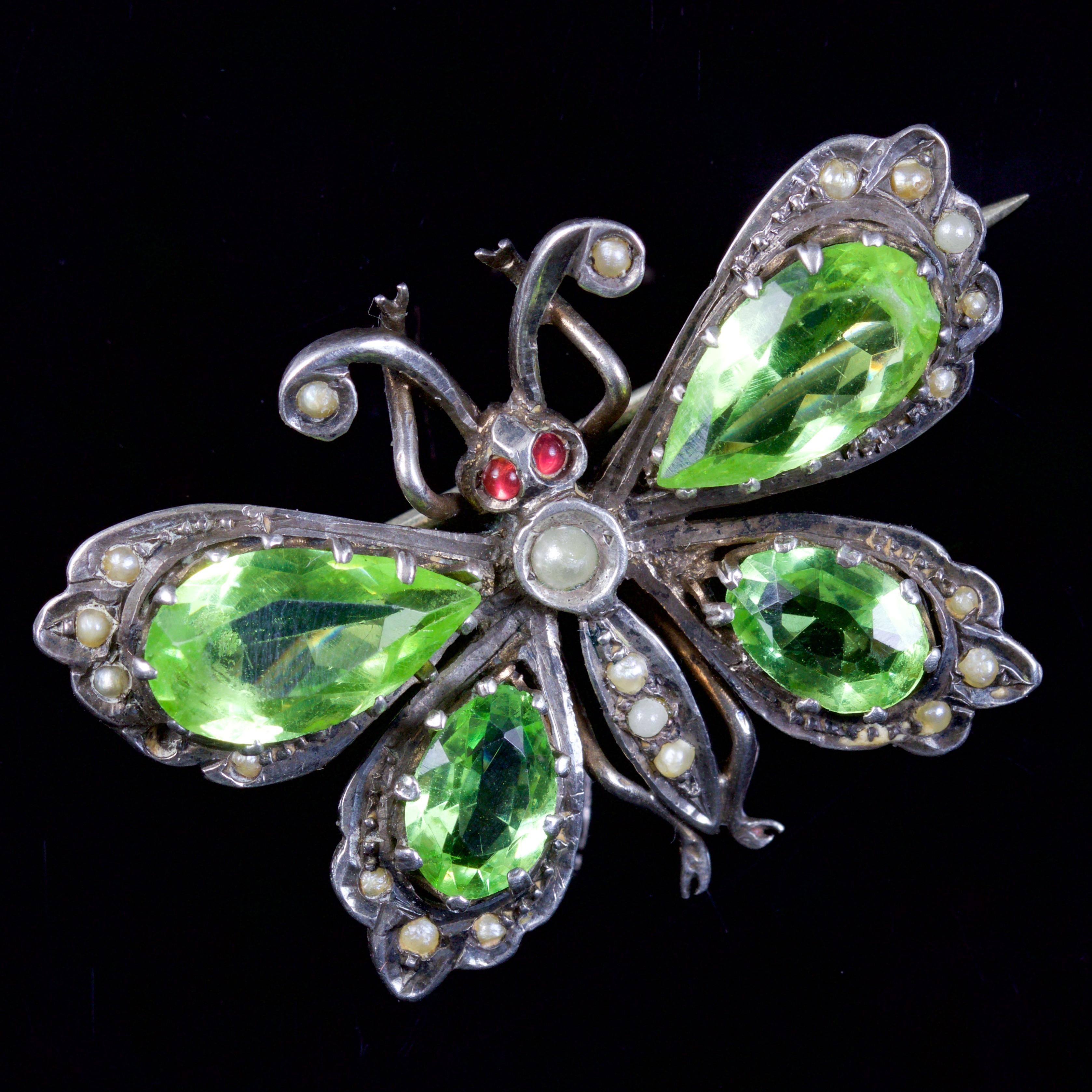 This beautiful Victorian butterfly brooch is, Circa 1880.

The brooch is adorned with green Paste Stone wings, Red paste Cabochon eyes, and pretty Pearls.

Paste is a heavy, very transparent flint glass that stimulates the fire and brilliance of
