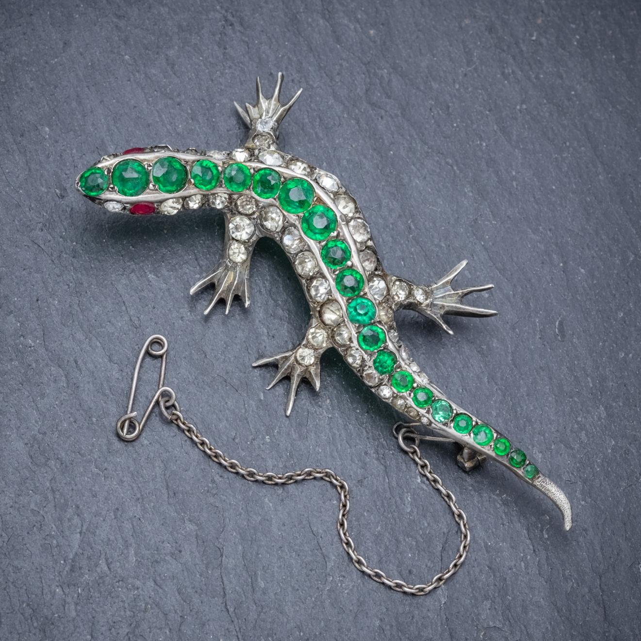 A delightful antique Victorian Lizard brooch crafted in Silver and decorated with sparkling white and green Paste Stones down the back with red Paste eyes at the head. 

The piece is three-dimensional and fitted with a sturdy pin, safety catch and