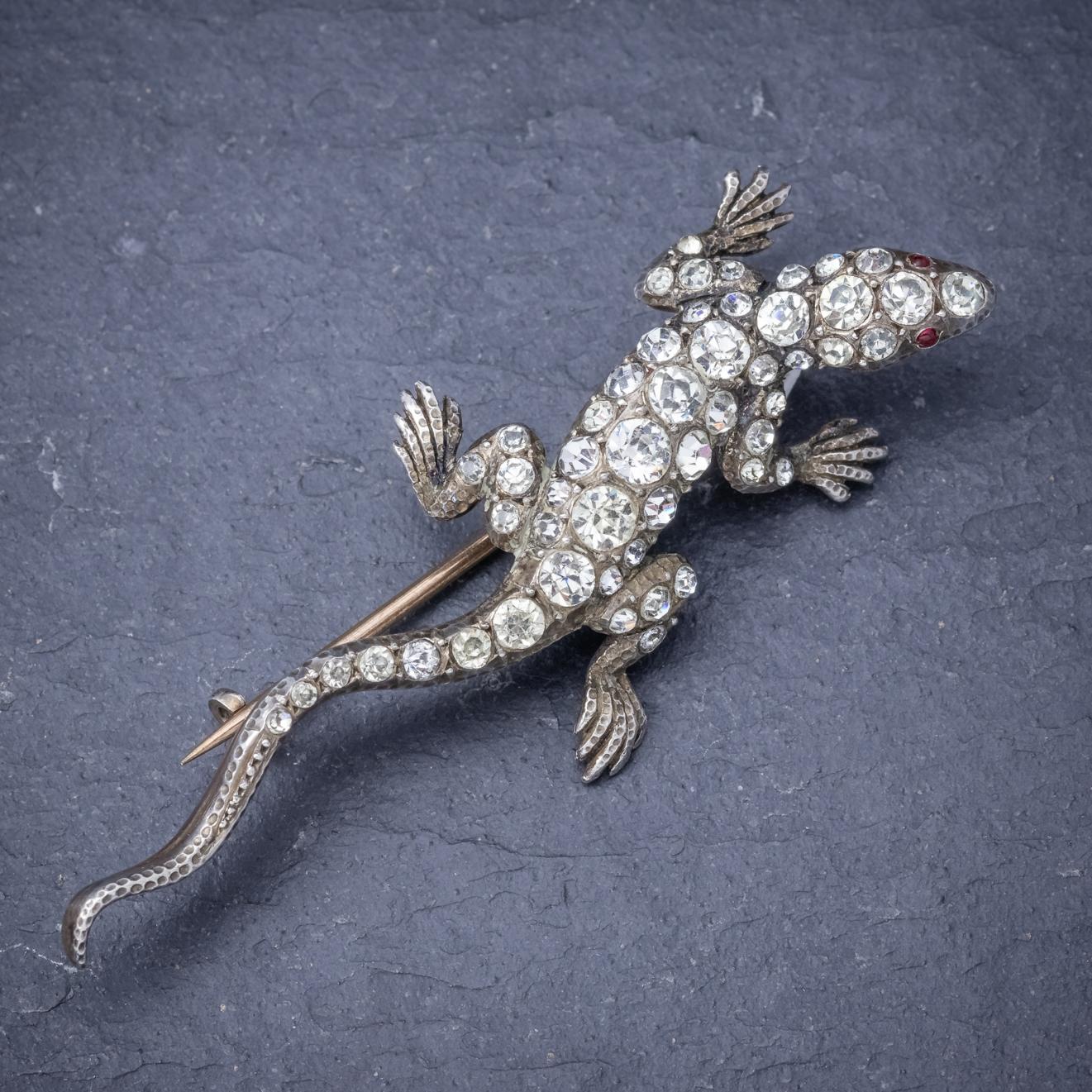 A splendid antique Victorian Lizard brooch decorated with red Paste eyes and a glistening array of clear Paste Stones along the back, head and tail which simulate the sparkle of Diamonds but at a fraction of the cost. 

The Lizard is
