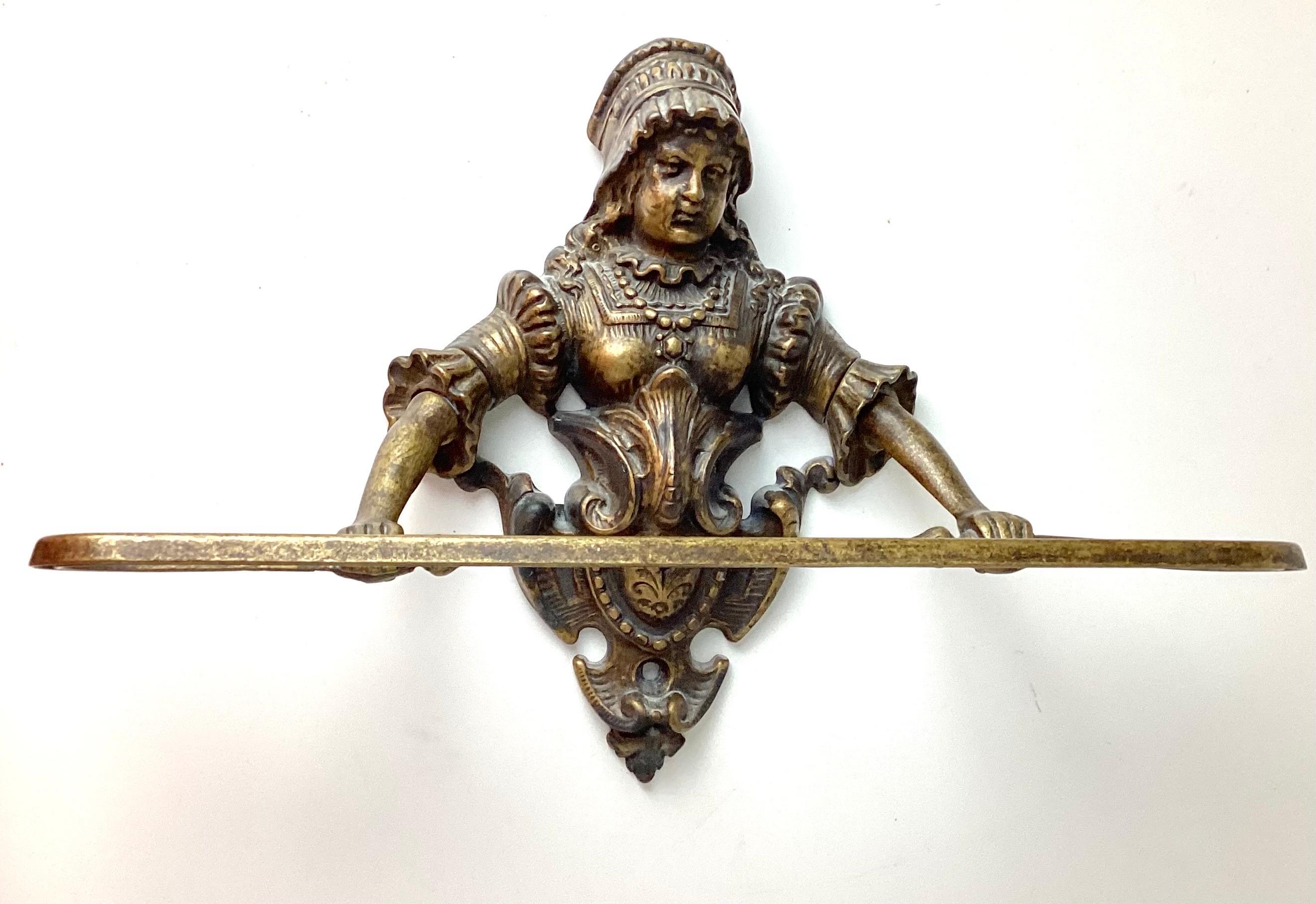 Cast brass figural wall mount kitchen or bathroom towel holder. The charming Victorian antique depicting a lovely woman (possibly milkmaid) in period dress above a brass crest, with a towel bar affixed to the woman’s hands. She is developing an