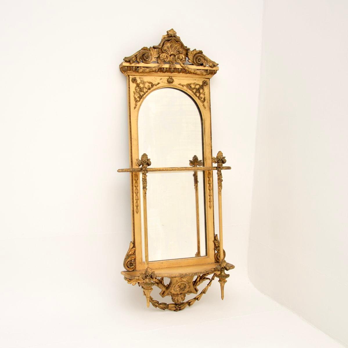 An absolutely stunning antique Victorian period gilt wood mirror. This was made in England, it dates from around the 1840-1850 period.

It is of incredibly fine quality, it is nice and slim with two built in shelves. There are lots of fine details