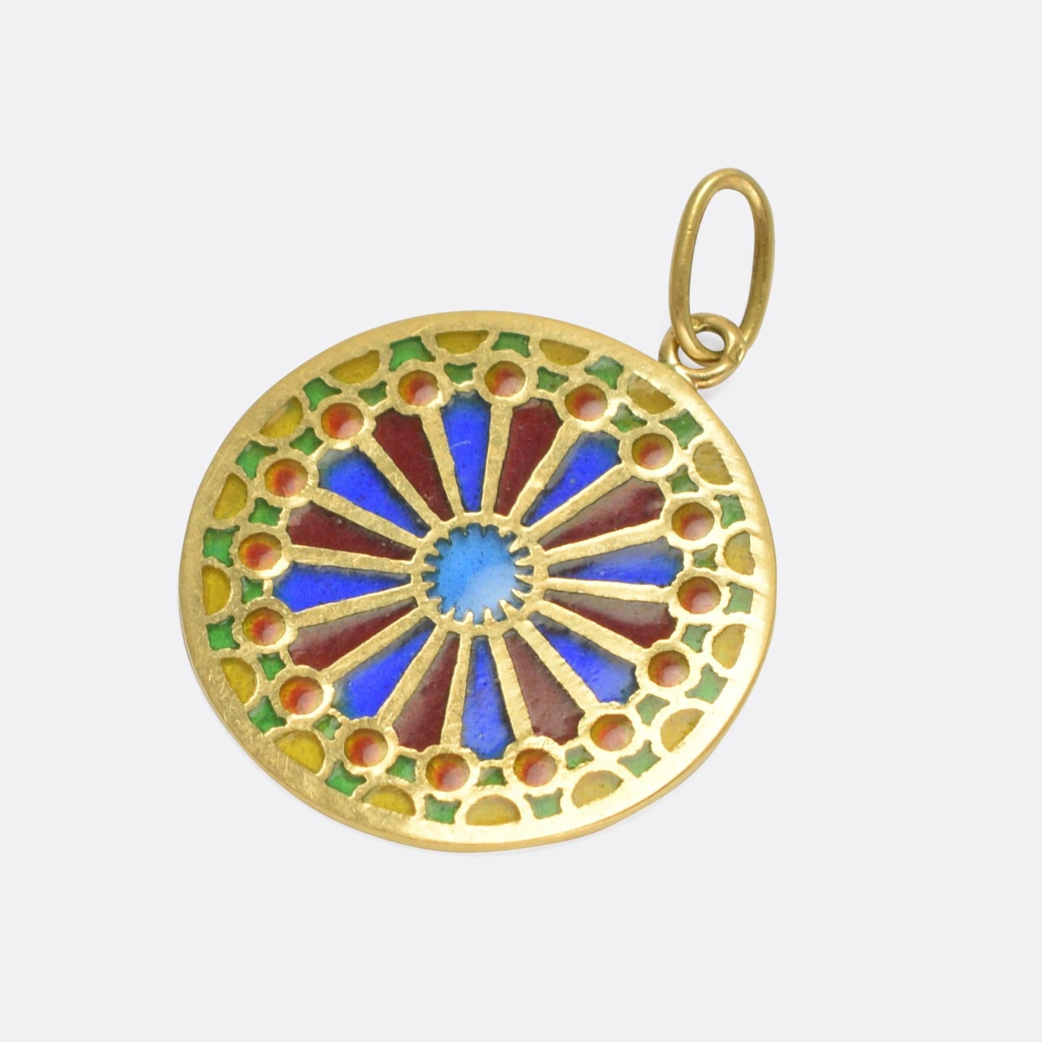 This beautiful antique pendant is finished in colourful plique-à-jour enamel. It has been modelled after the North Rose Window at Notre Dame Cathedral in Paris, and is fashioned in 18k yellow gold.

The term plique-à-jour literally translates into