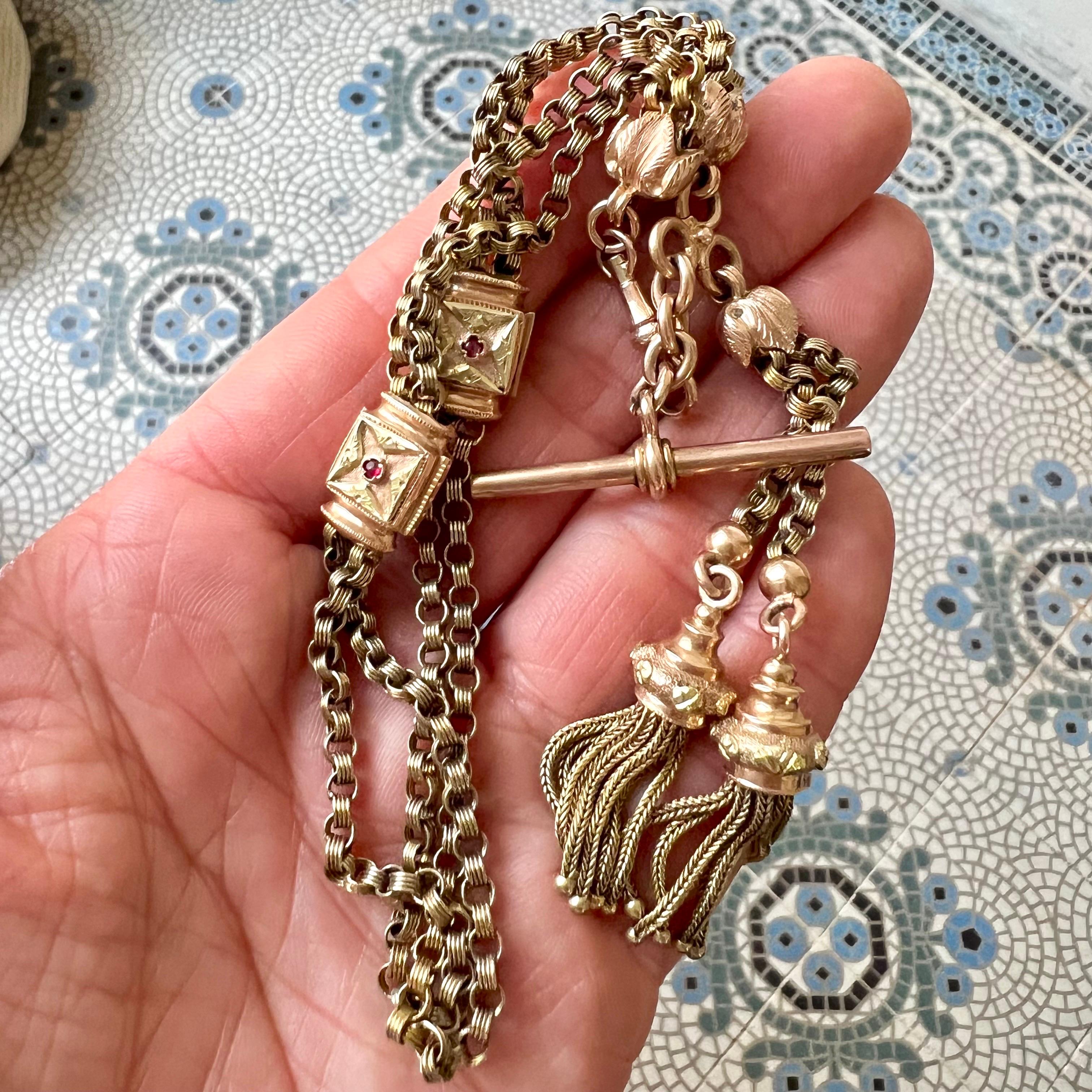 Una antigua cadena de reloj de bolsillo victoriano engastada con rubíes, una barra en T y un colgante de borlas - una llamativa pieza de joyería de la época victoriana, esta cadena suele datar de mediados a finales del siglo XIX. 

La cadena está