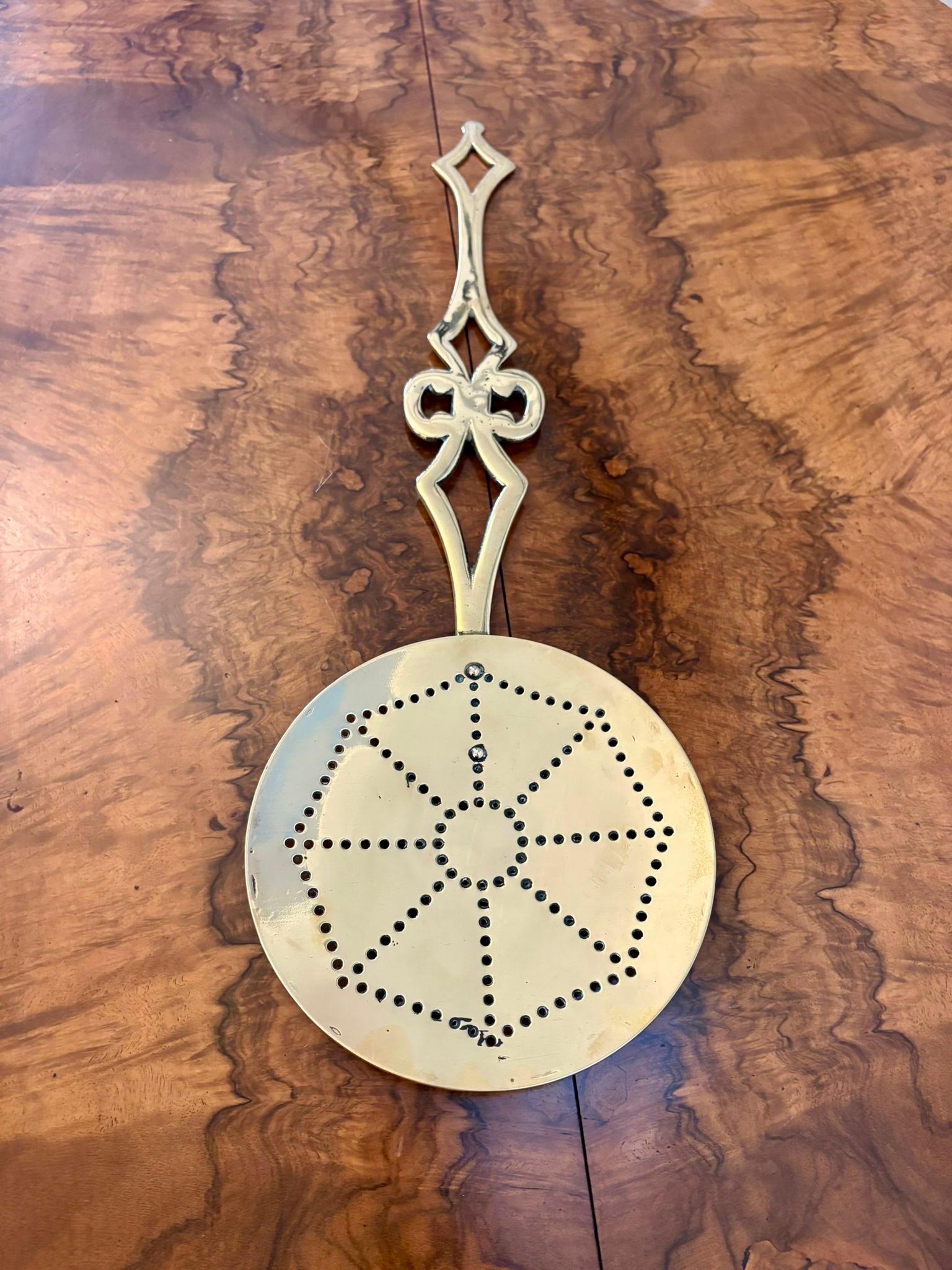 Antique Victorian quality brass skimmer having a shaped handle attached to a round brass skinner with spider web decoration.

A lovely decorative piece.  Antique brass skimmers were primarily used for skimming the surface of liquids, especially in