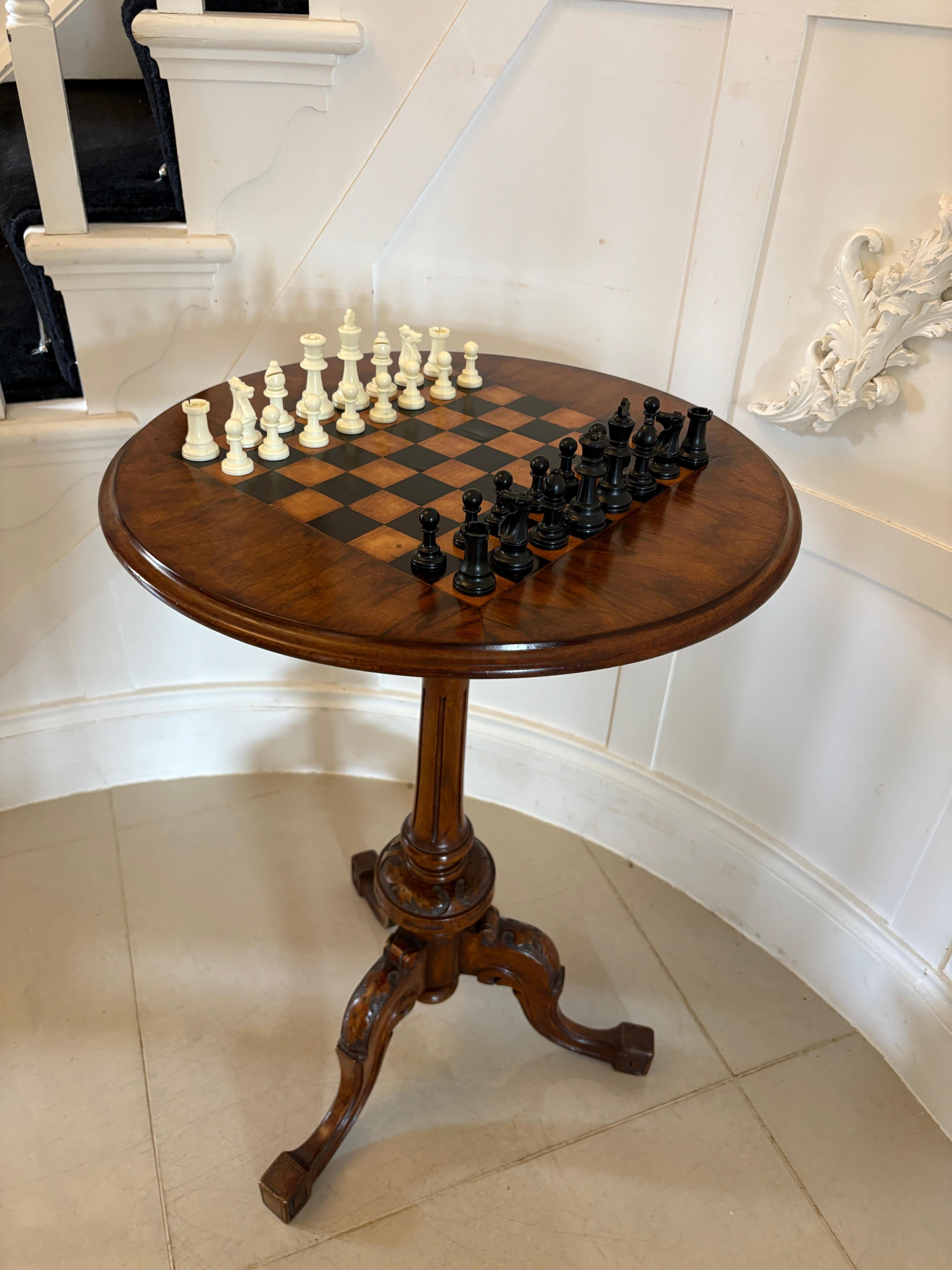 Ancienne table à jeux victorienne en ronce de noyer avec un plateau circulaire en ronce de noyer avec un échiquier incrusté soutenu par un piédestal en ronce de noyer tourné et sculpté reposant sur trois pieds cabriole en noyer sculpté. 

Une pièce