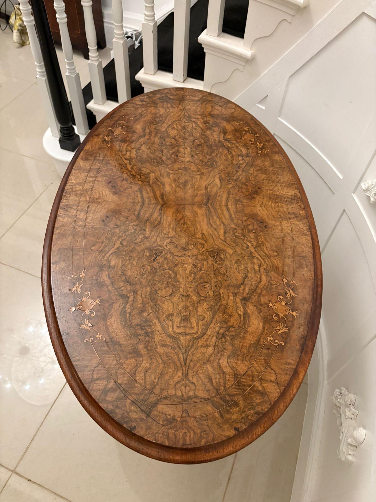 Ancienne table de lampe ovale victorienne en ronce de noyer incrustée avec un plateau ovale en ronce de noyer incrustée avec un bord mouluré soutenu par quatre colonnes en noyer massif tournées et cannelées reposant sur quatre pieds cabriole en