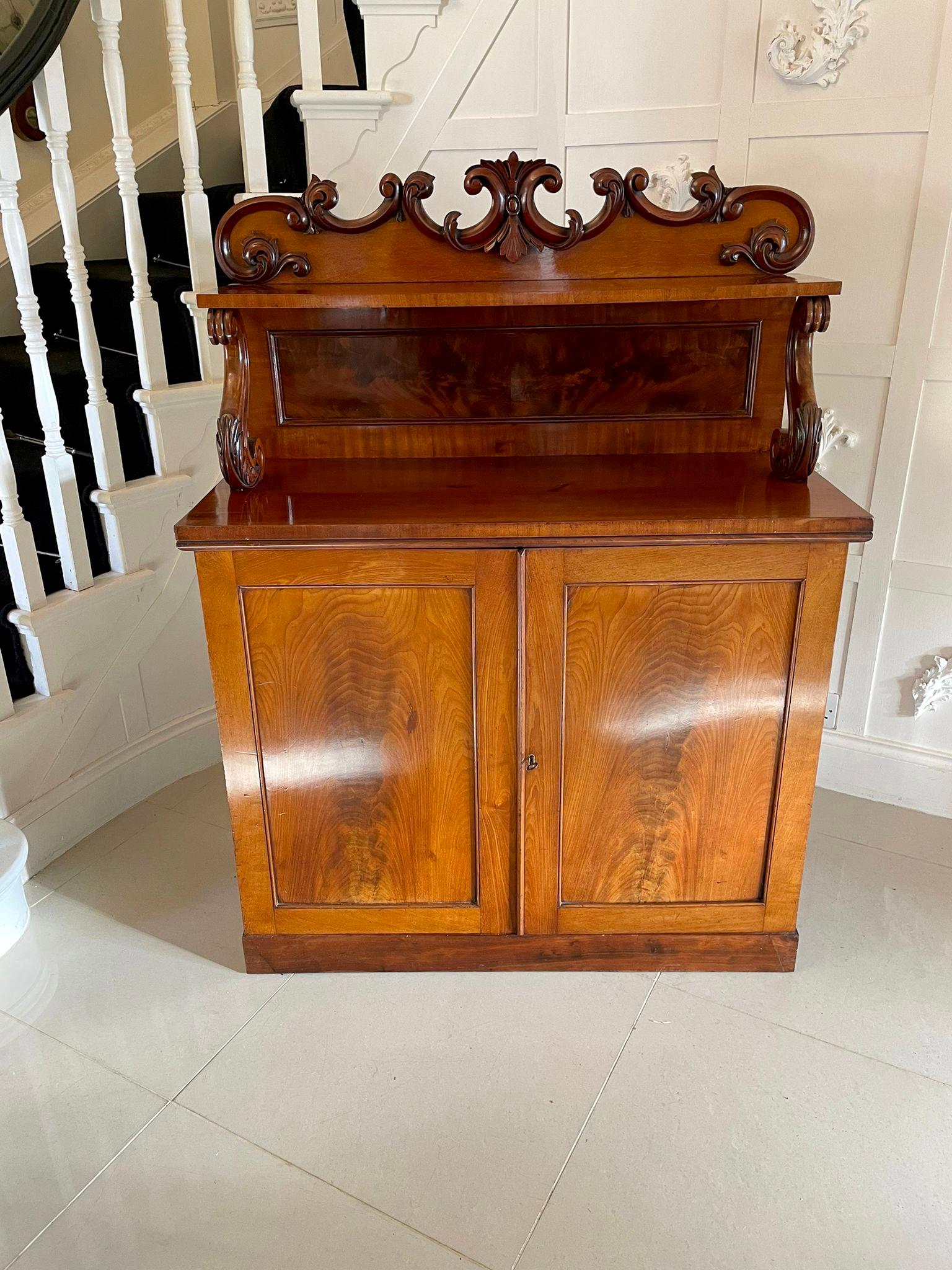 Antique Victorian quality carved mahogany sideboard having a quality carved mahogany shaped pediment over a shelf supported by s shaped carved mahogany supports. A quality mahogany rectangular shaped top above two quality figured mahogany panelled