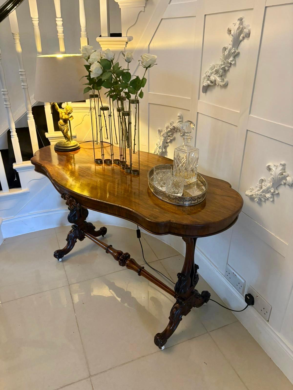 Table centrale autoportante en bois de rose sculpté de qualité victorienne, avec un plateau en forme de serpentin en bois de rose de qualité, une frise en bois de rose sculpté soutenue par des extrémités en volutes en bois de rose sculpté, reposant