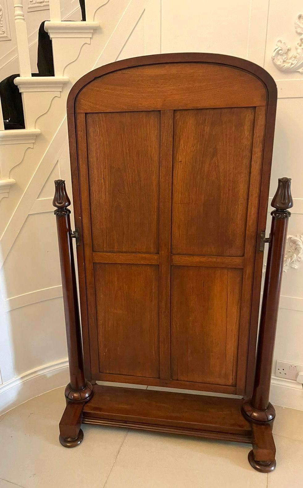 Antique Victorian quality figured mahogany free standing cheval mirror having a large adjustable arched top, quality figured mahogany cheval mirror flanked by figured mahogany columns with carved tulips tops supported by a figured mahogany base with