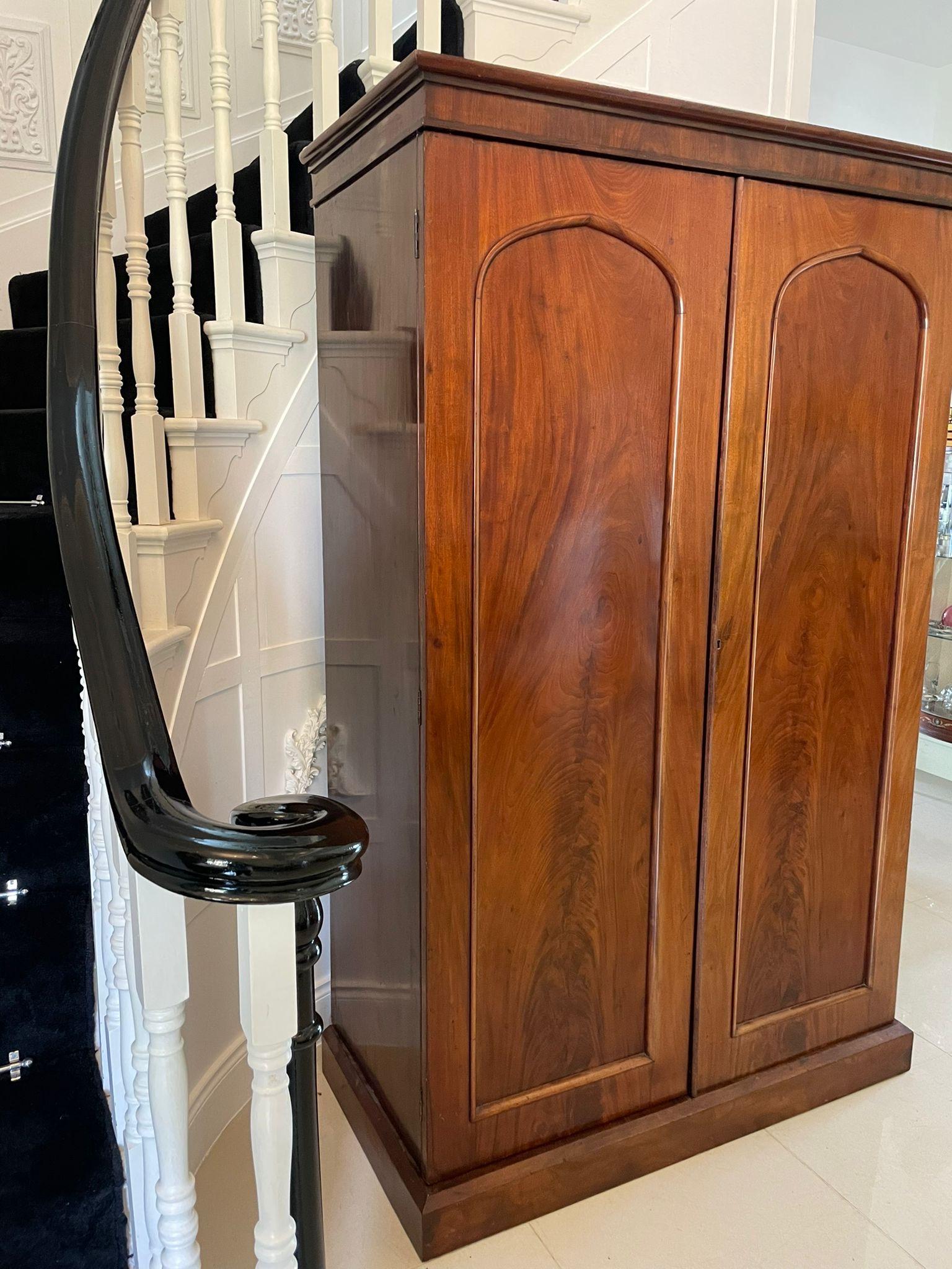 Antique Victorian quality figured mahogany wardrobe having a moulded cornice above a pair of figured mahogany panelled doors opening to reveal a fitted mirror, hanging compartment, four sliding trays and three drawers with original brass handles