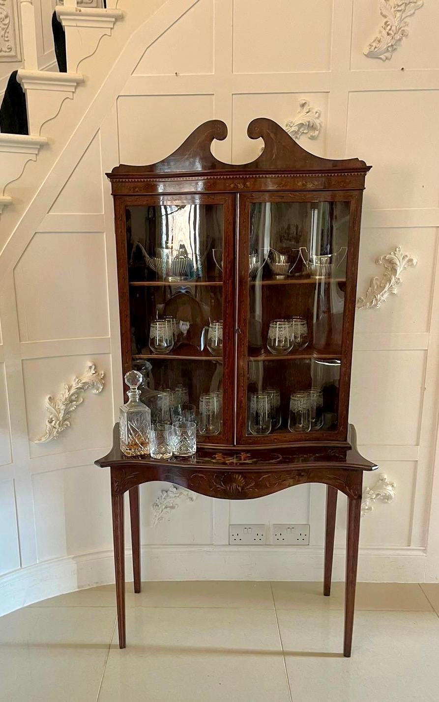 Antique Victorian quality mahogany display cabinet with original painted decoration having a swan neck pediment above a pair of mahogany serpentine shaped glazed doors with original painted decoration opening to reveal two adjustable display shelves