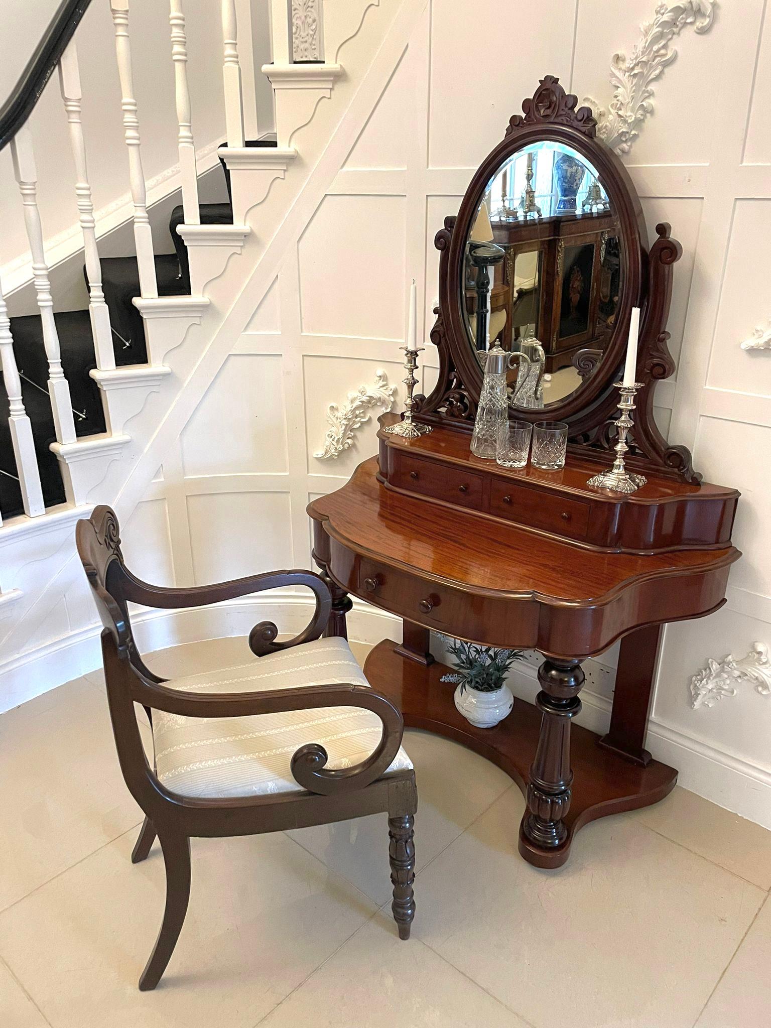 Antique Victorian quality mahogany dressing table having a quality oval bevelled edge mirror in a mahogany frame with a carved top supported by carved mahogany supports above two drawers with original turned knobs above a mahogany top with a thumb