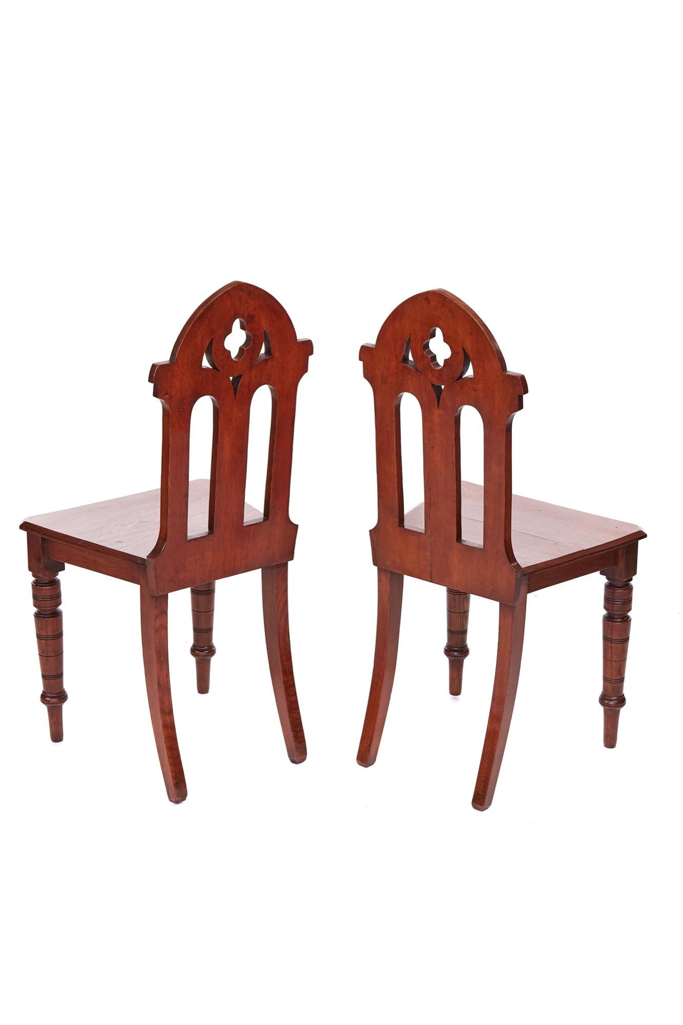 Antique Victorian quality pair of oak gothic hall chairs having carved oak backs with shaped turned legs to the front and outswept legs to the back. Lovely color and condition.

Measures: H 88.5cm, W 43cm, D 32.5cm.