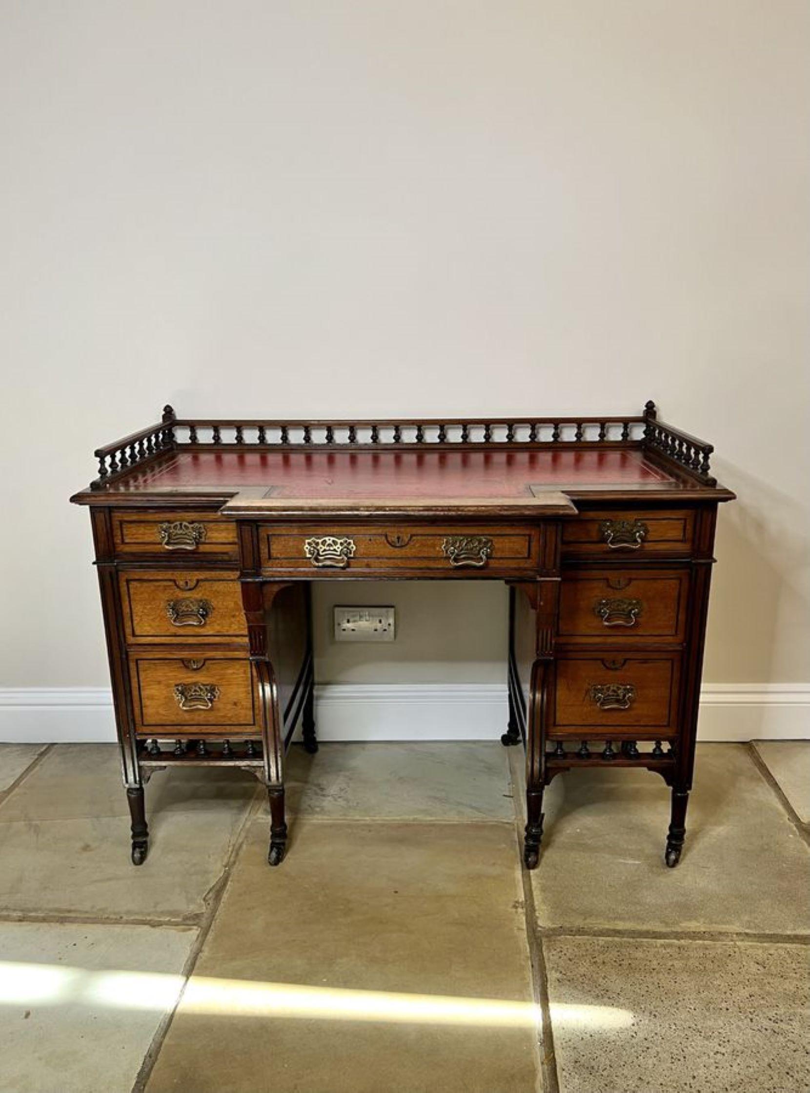 Antique Victorian quality walnut leather top freestanding kneehole desk having the original gallery back and red leather writing surface above seven drawers with the original brass handles, freestanding polished back standing on turned legs with the
