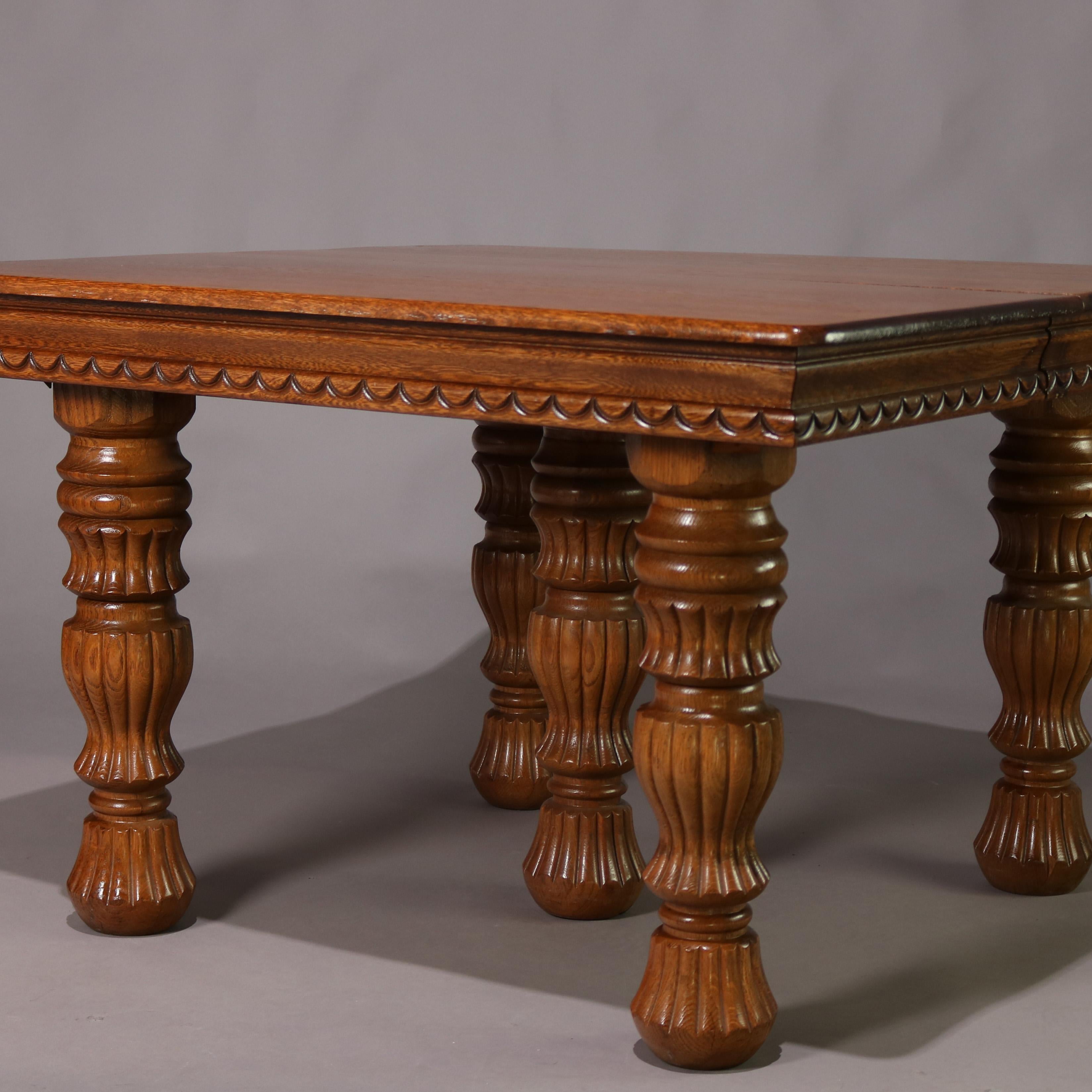 An antique Victorian dining table features quarter sawn oak construction with top surmounting carved skirt and raised on reeded baluster legs, square table extends to include two 10