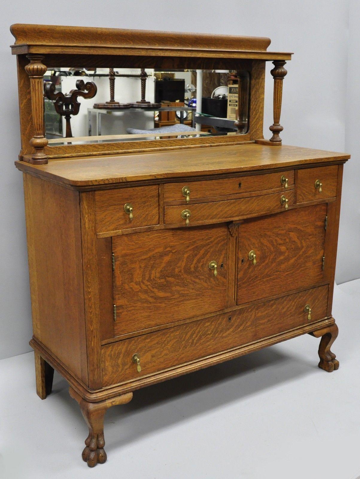 Antique Quartersawn golden oak paw foot sideboard with mirrored backsplash. Item features carved paw feet, bow front, beautiful woodgrain, two swing doors, no key but unlocked, bevelled glass mirror, five dovetailed drawers, circa