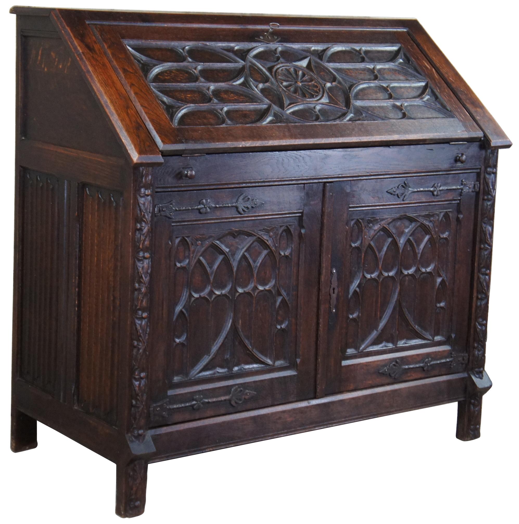 Antique Jacobean secretary desk. Made of oak, featuring Gothic style carvings with iron hardware accents. Measure: 41