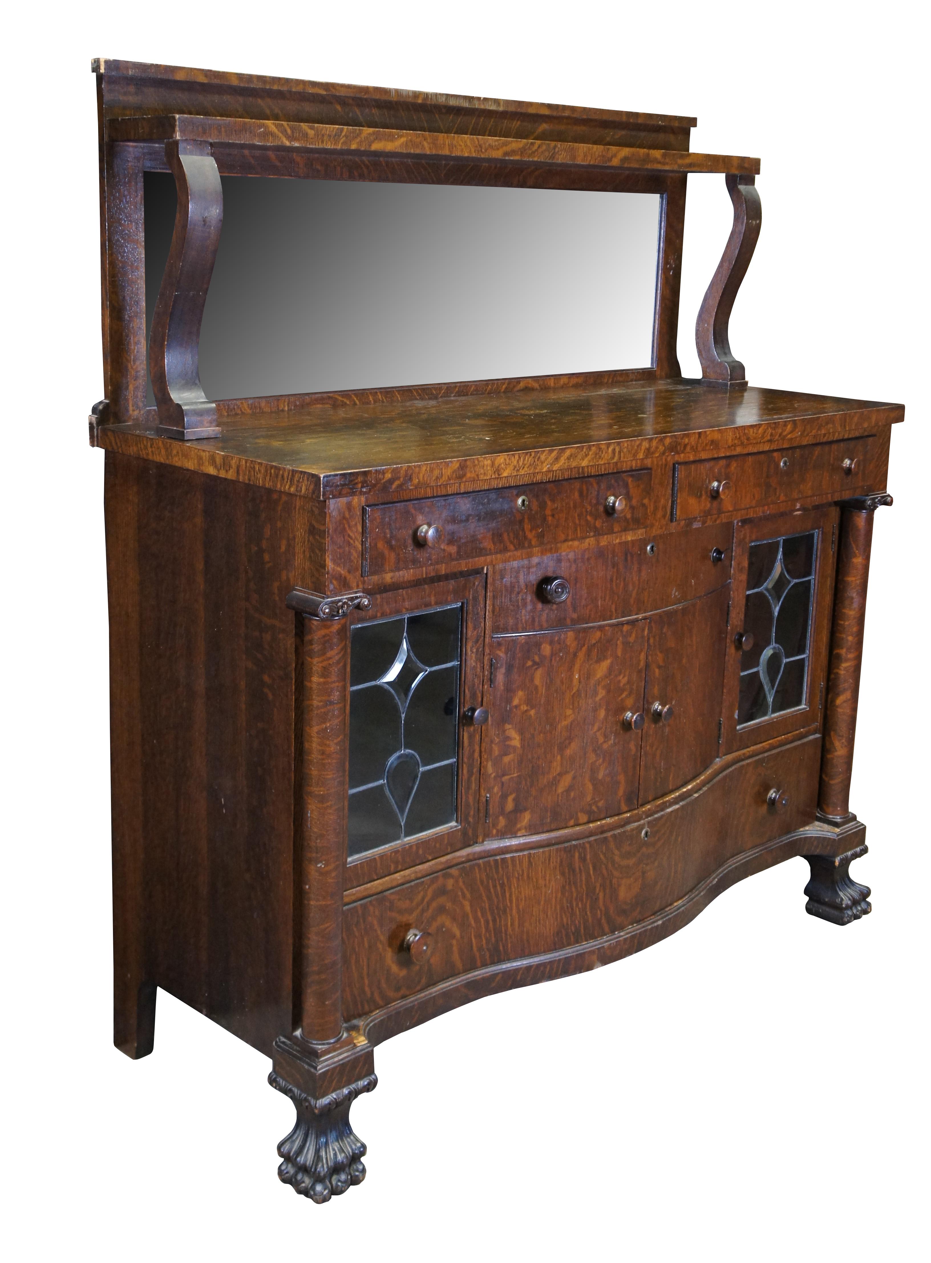 Antique Victorian parlor buffet / sideboard / bar back / dry server cabinet.  Made of quartersawn oak featuring Mission and Empire styling with a beveled mirror backsplash over rectangular top supported by lower demilune cabinet with leaded glass