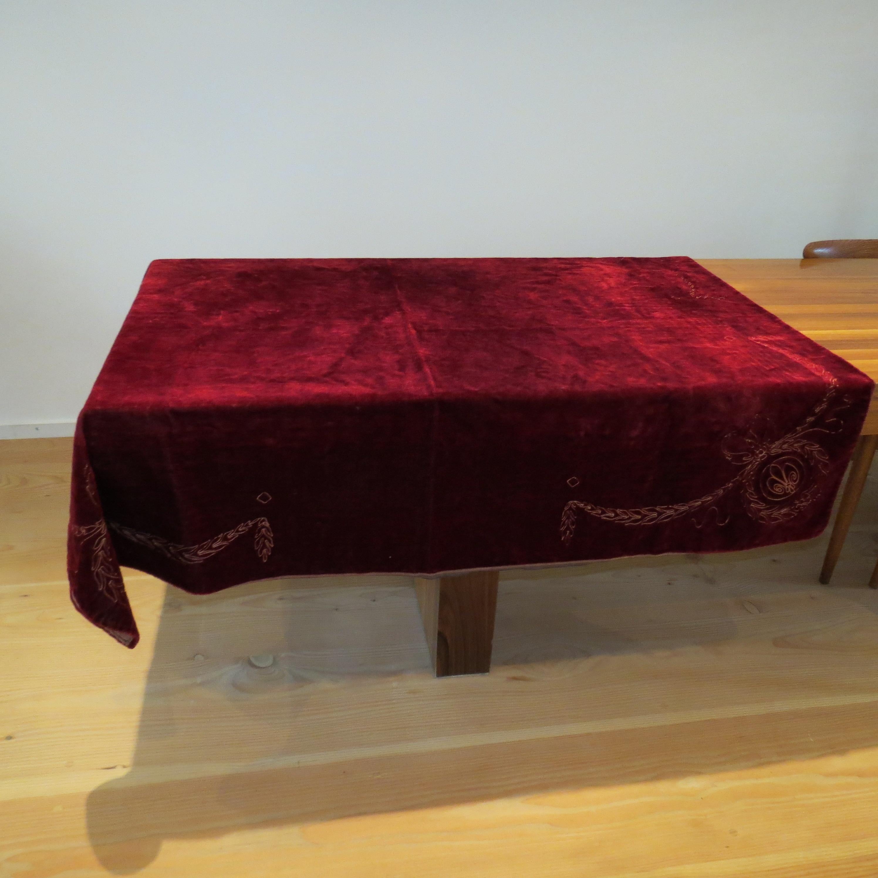Antique, opulent, red velvet tablecloth from the 1900s.  Wonderful hand crafted piece with hand stitched embroidery to each corner of the cloth.  Used originally as a tablecloth, there are signs of wear to the fabric as a result of being laid on a