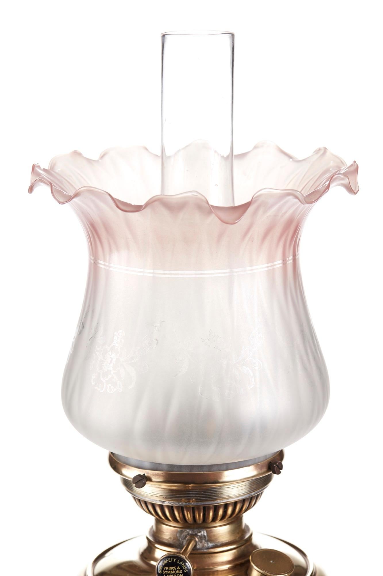 Antique Victorian reeded column brass oil lamp having a pretty tulip shaped white and pink etched glass shade with a single burner stood on a square stepped brass base.
  
