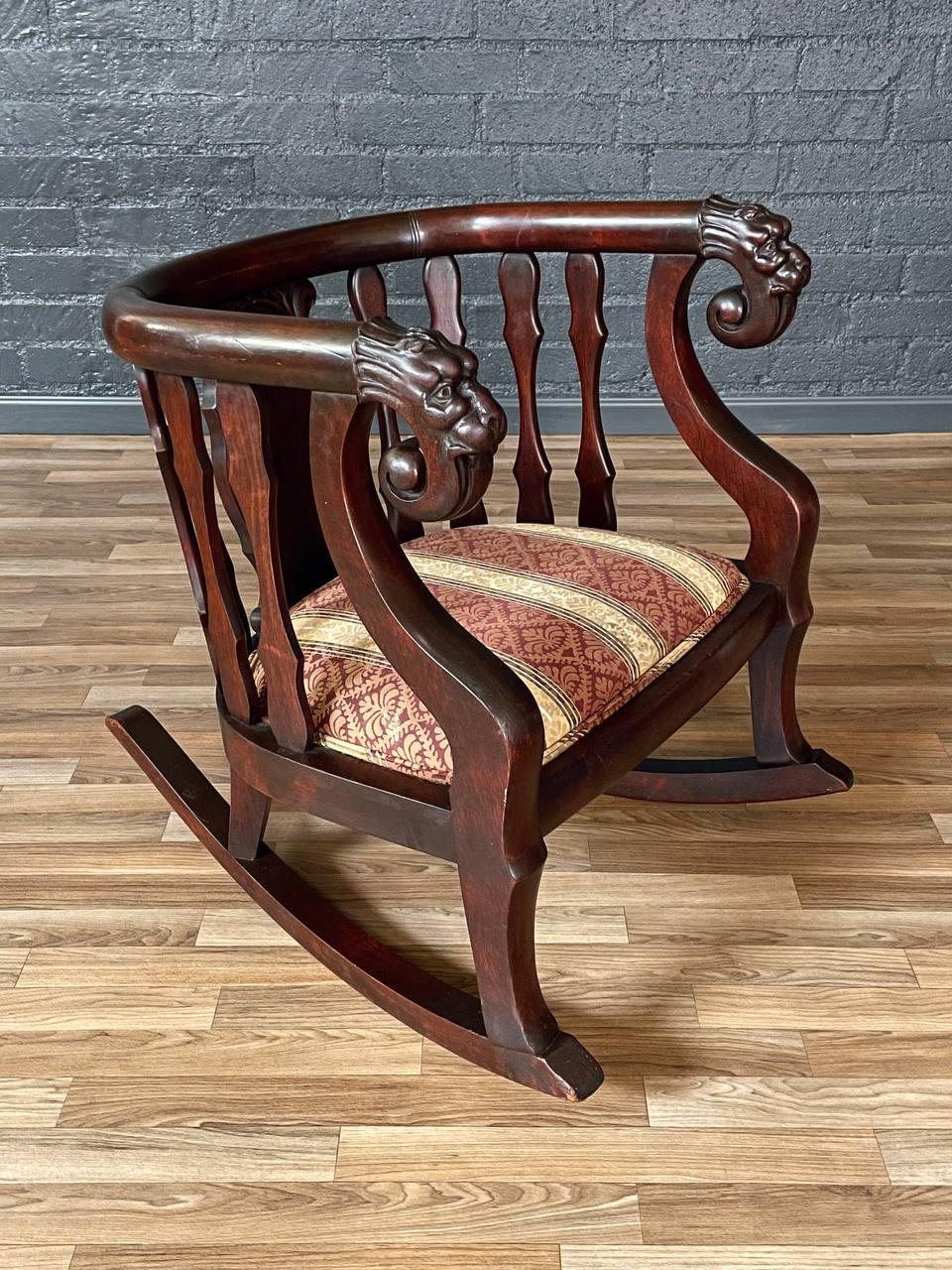 Condition: Original Vintage Condition
Materials: Mahogany, Original Upholstery 
Style: Victorian Renaissance Revival 

Crafted in the 1920s, this antique barrel-back rocking chair embodies the bold elegance of the Victorian Renaissance Revival era.