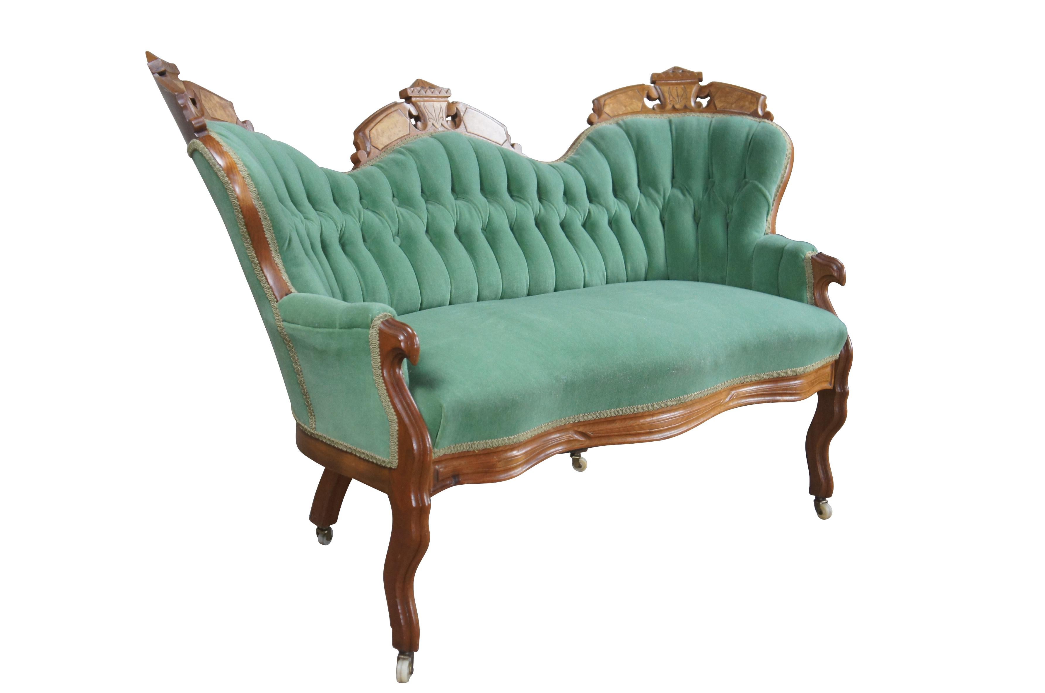 Antique Victorian Renaissance Revival parlor Settee.  Made from walnut with a serpentine form featuring a carved camelback with burled panels.  Upholstered in a green velvet / velour with a tufted back.  The settee is supported by contoured legs