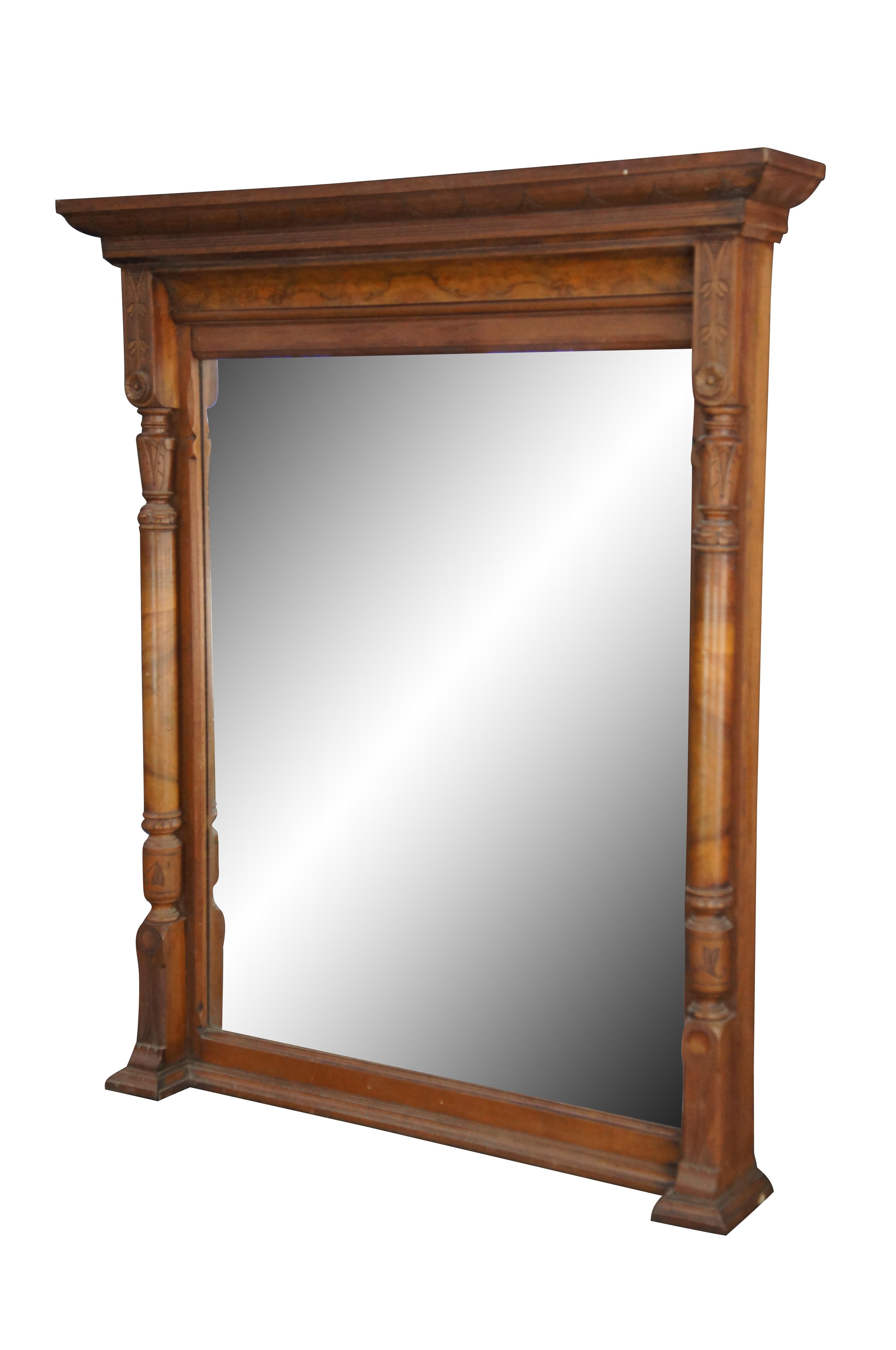 Monumental antique Renaissance Revival Overmantel wall mirror, circa 1870s.  Features a walnut burl frame with full columns centered between a large mirrored glass plate.  The columns are carved throughout with elegant foliate detail.  Crown molding