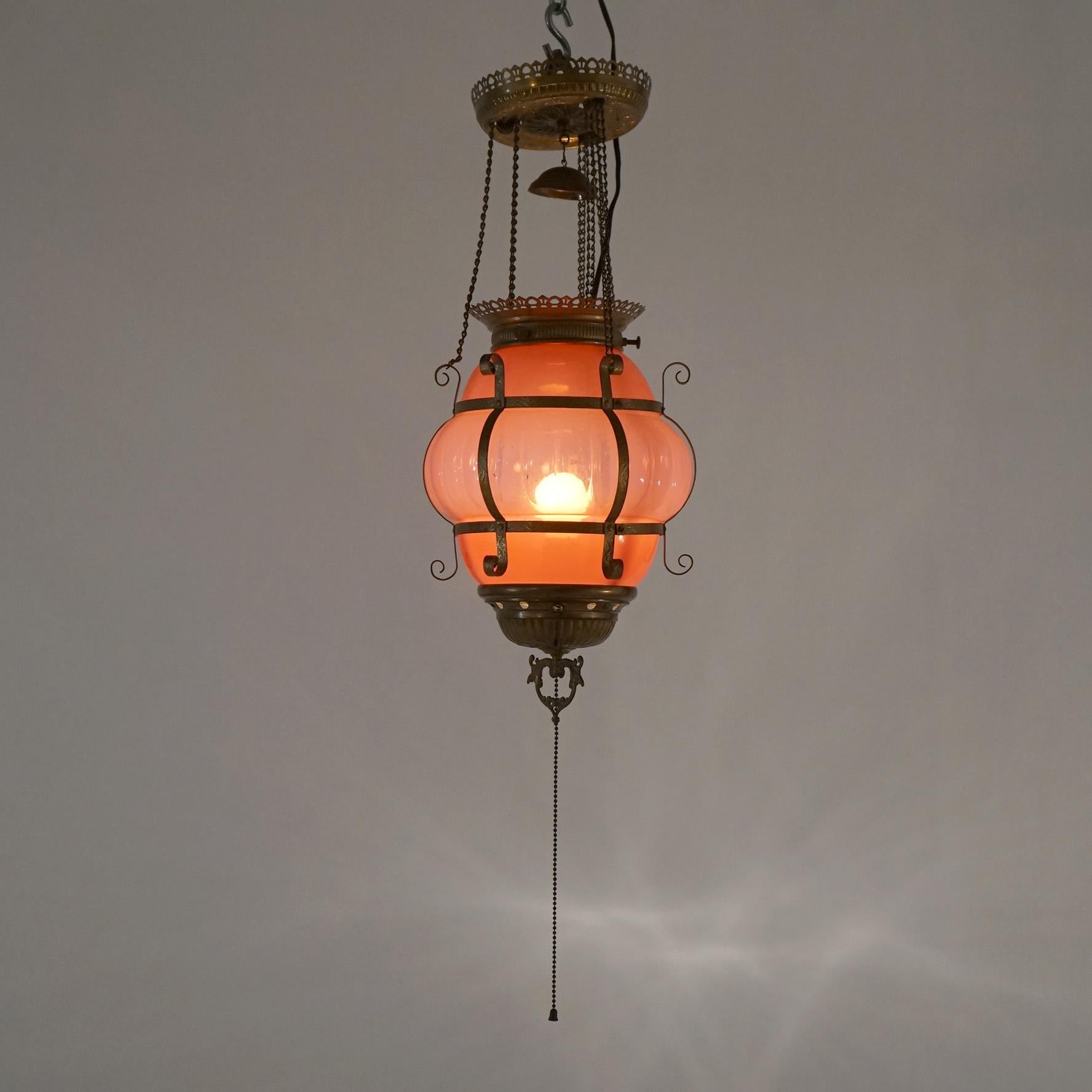 An antique Victorian hanging pendant hall light offers scroll form brass frame with ribbed cranberry opalescent glass globe, c1890

Measures- 21.5''H x 8.5''W x 8.5''D; 8'' drop