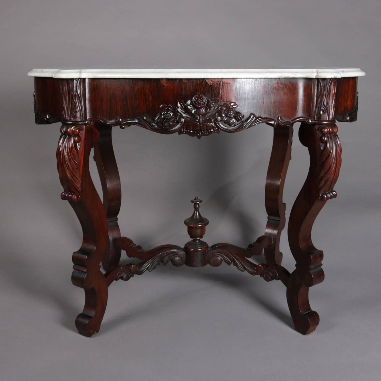 Antique Victorian Rococo carved rosewood parlor table features turtle top beveled marble supported by deep serpentine apron with floral carving, raised on scroll form cabriole legs with carved acanthus knees having scroll and acanthus stretchers
