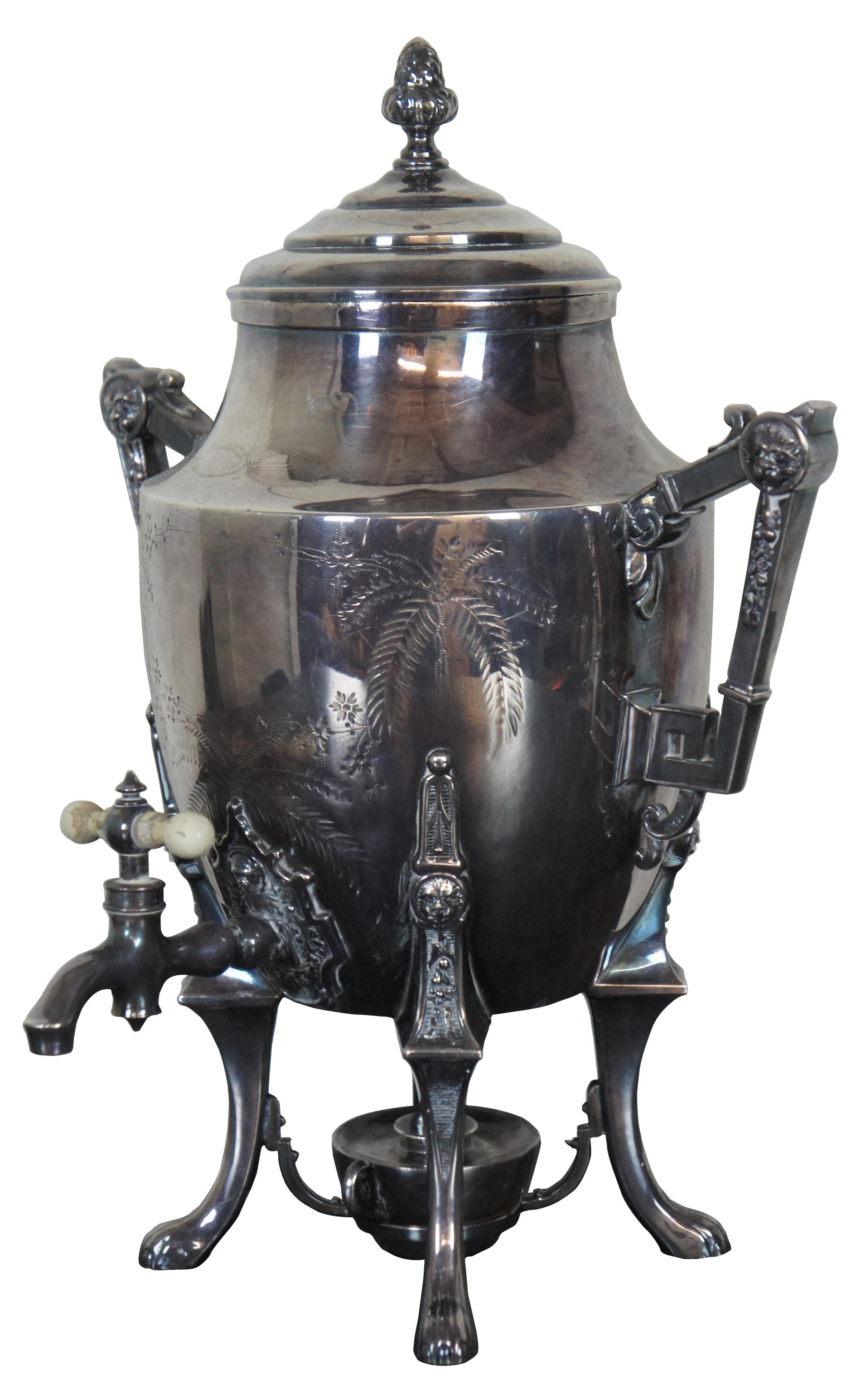 Antique silver plated coffee urn and burner by Rogers Smith & Co of New Haven, Connecticut. Decorated with engraved palm trees, floral and lions head accents and acorn finial. Measure: 16