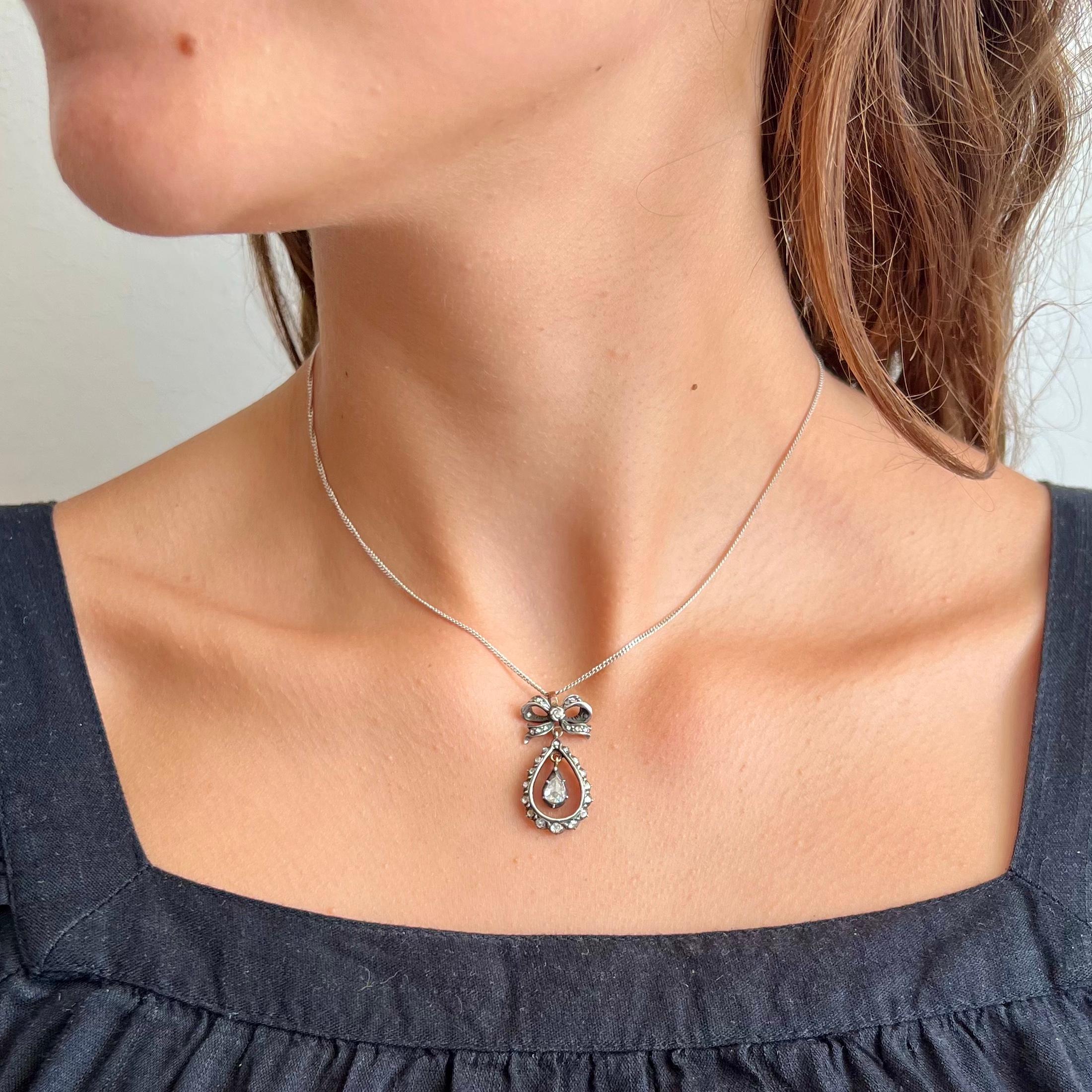 This antique Victorian drop-shaped bow pendant designed with rose cut diamonds is truly a treasure to behold. The pendant is created with rose cut diamonds set in a teardrop shape surrounding a dangling tear drop shape featuring a pear cut diamond.