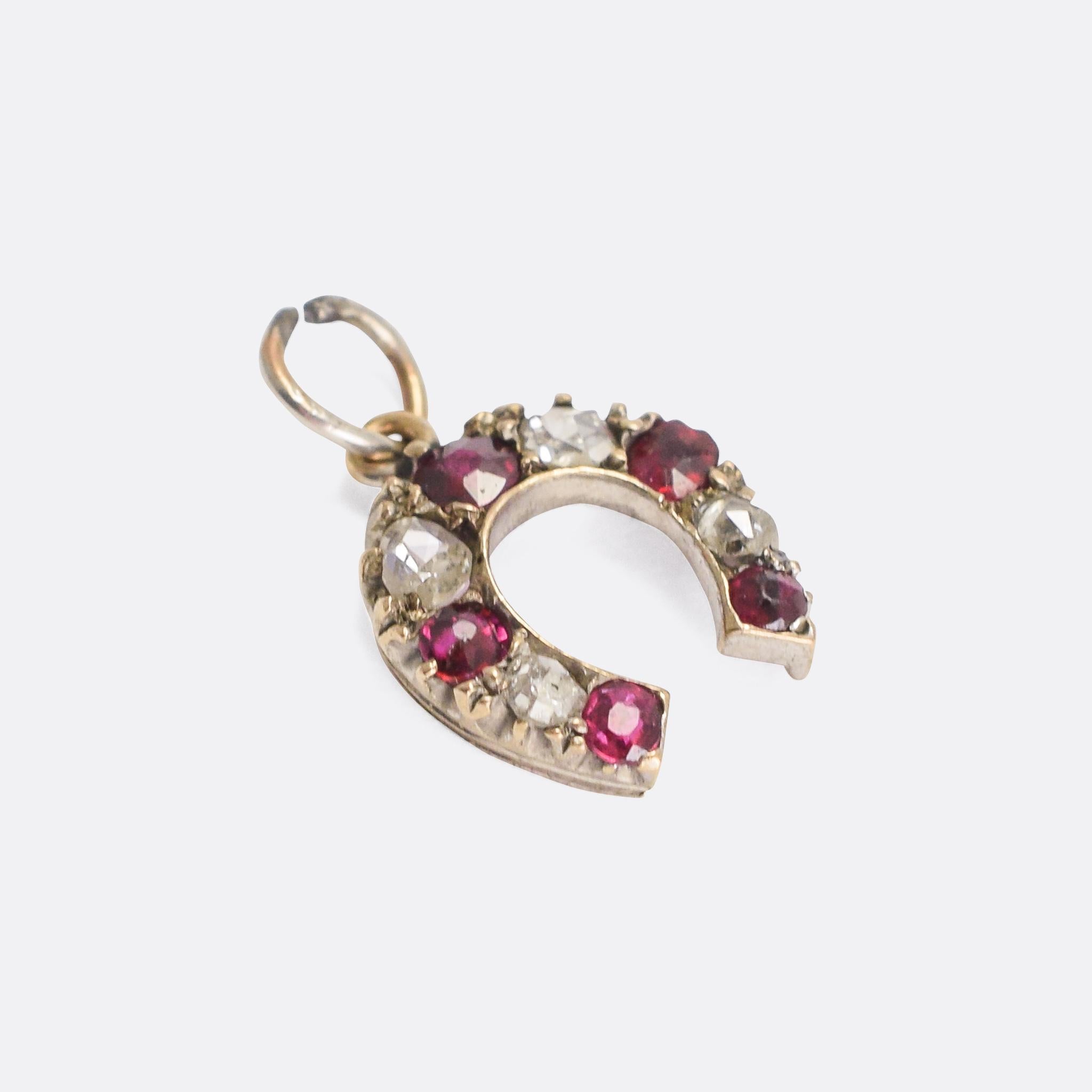 A sweet petite antique horseshoe pendant set with rubies and rose cut diamonds. Dating from the late Victorian era, it's modelled in 9 karat yellow gold with silver settings. A perfect addition to your charm bracelet, or for wear as a single